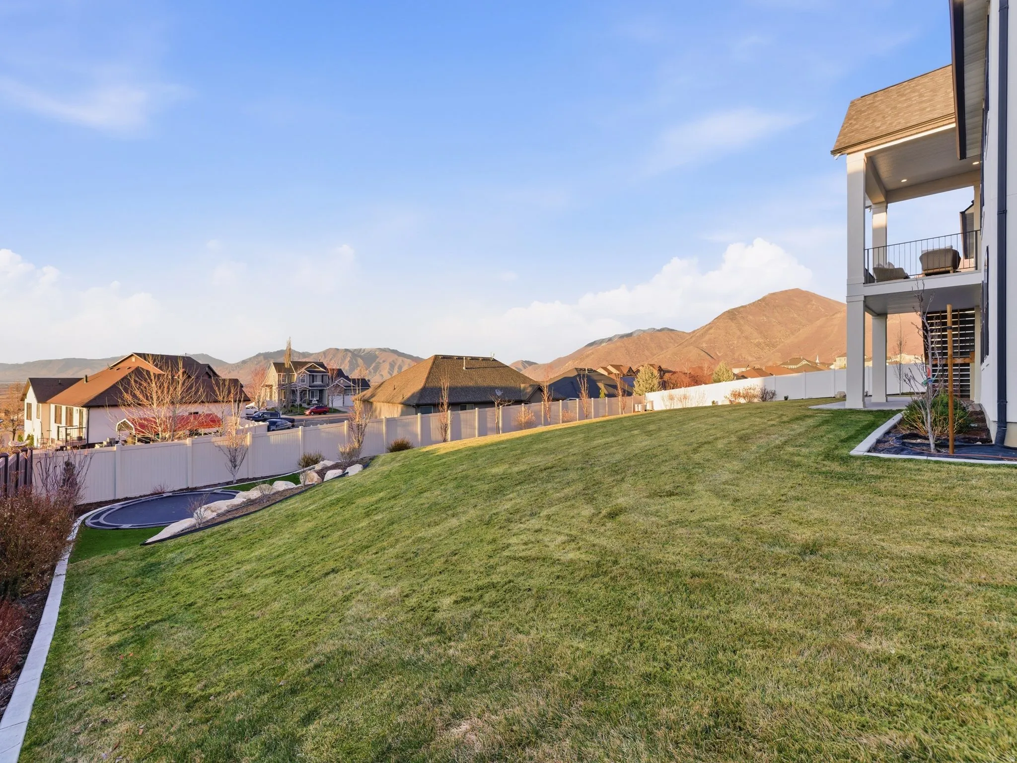Fenced backyard with a mountain view, a patio, a balcony, and a residential view