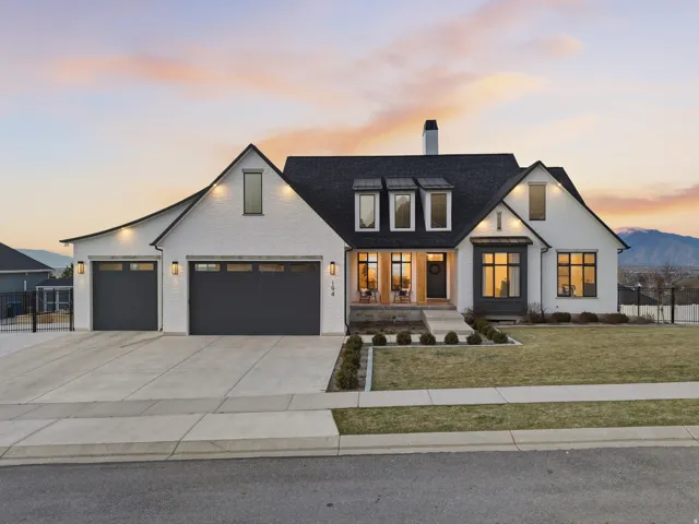 Modern farmhouse style home featuring a garage, a chimney, driveway, and brick siding