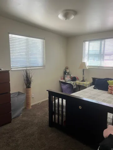 Bedroom featuring dark colored carpet and baseboards