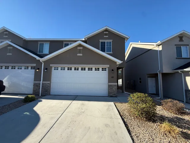 Traditional home featuring stone siding, concrete driveway, stucco siding, and an attached garage