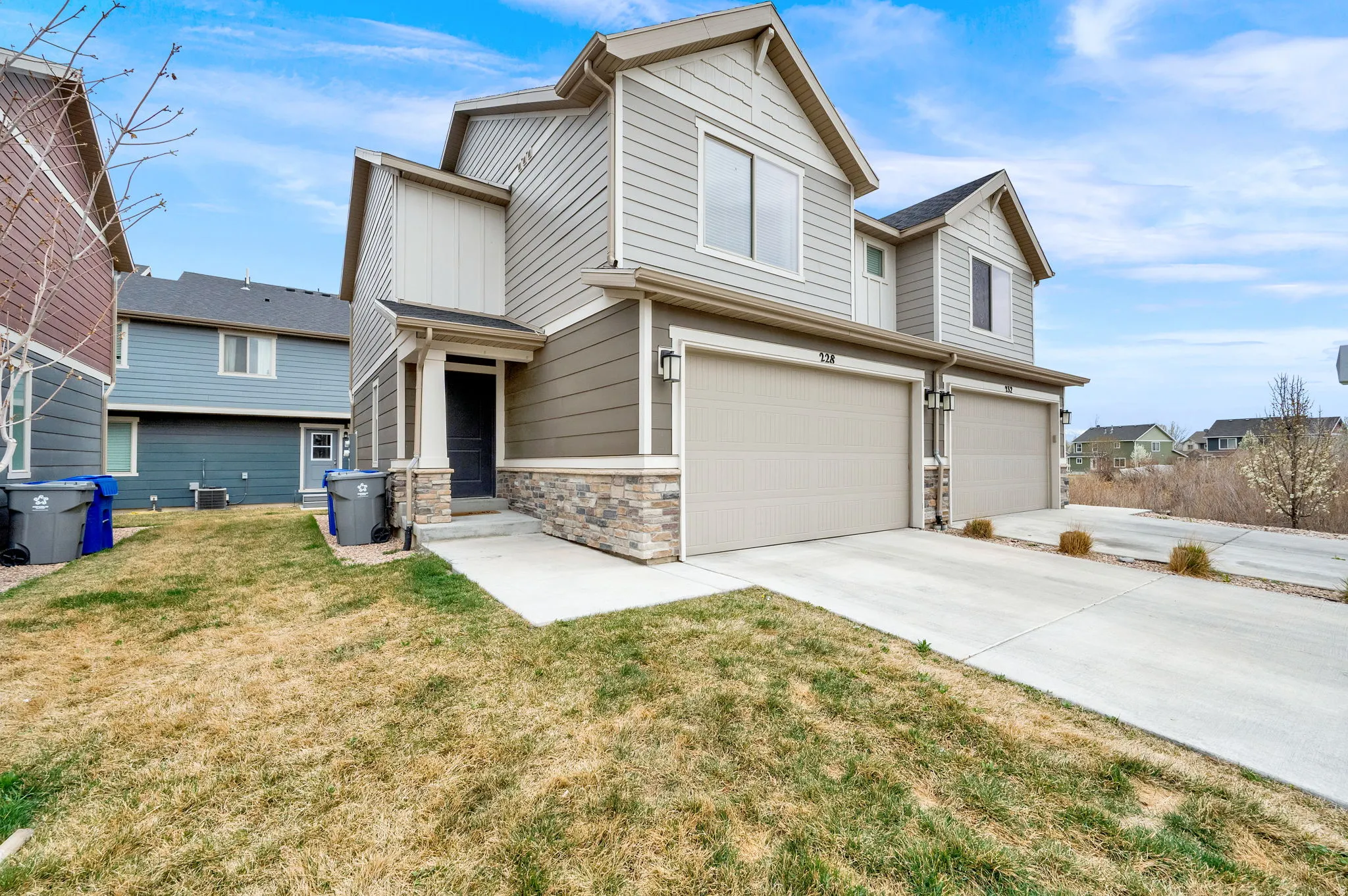 View of front of home with an attached garage, stone siding, a front lawn, and concrete driveway