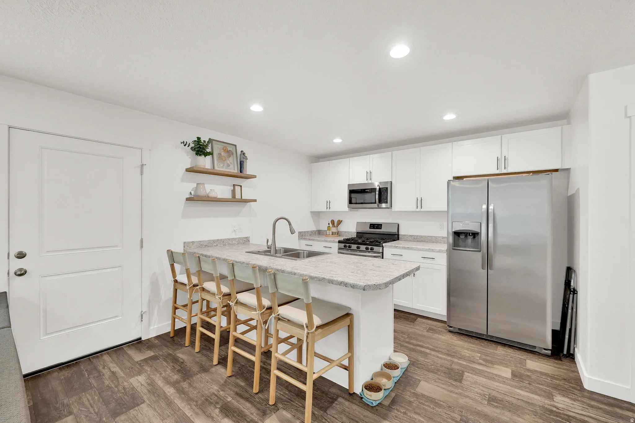 Kitchen with a peninsula, white cabinets, a breakfast bar area, stainless steel appliances, and light countertops