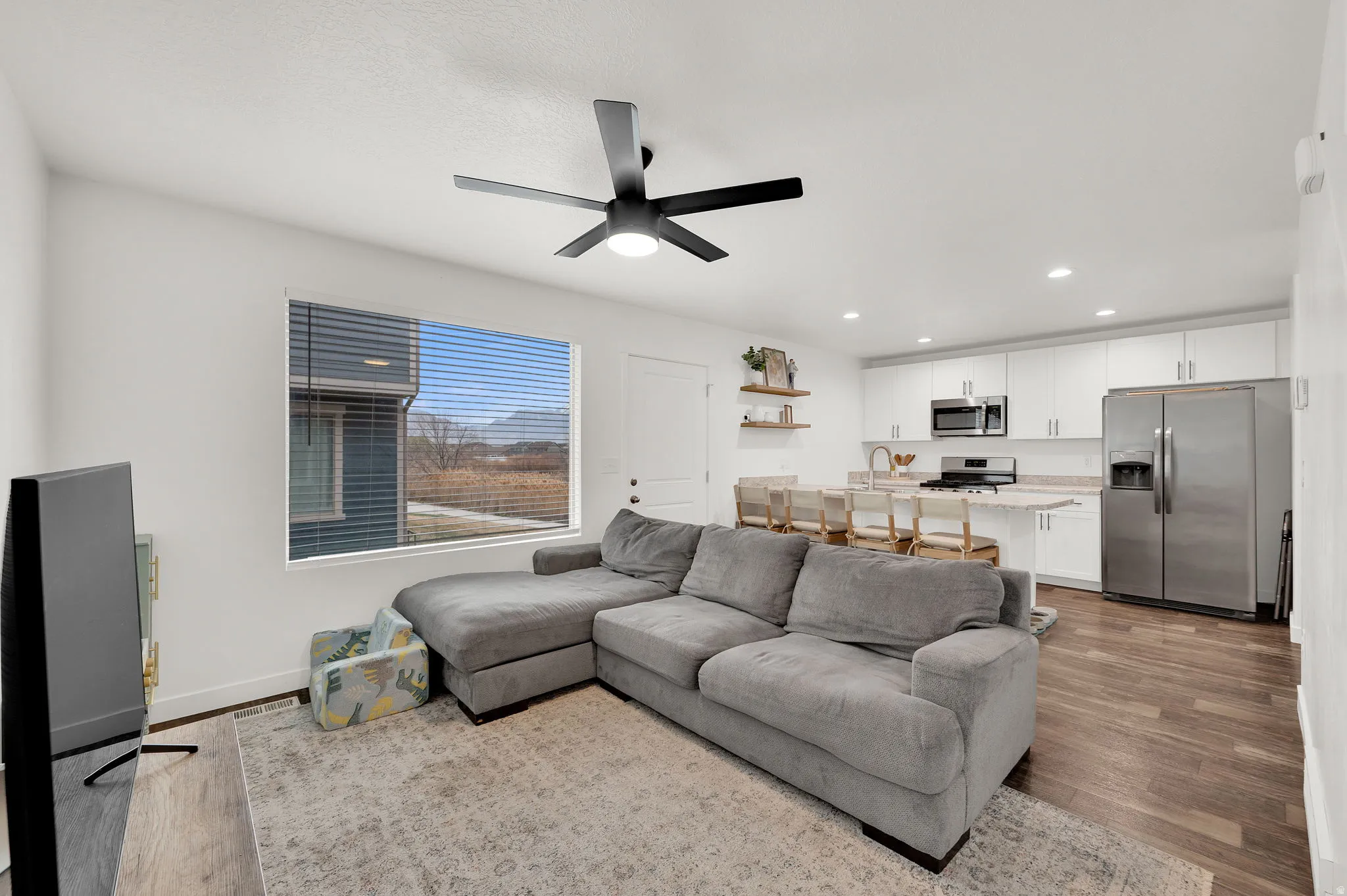 Living area with a ceiling fan, light wood finished floors, and recessed lighting