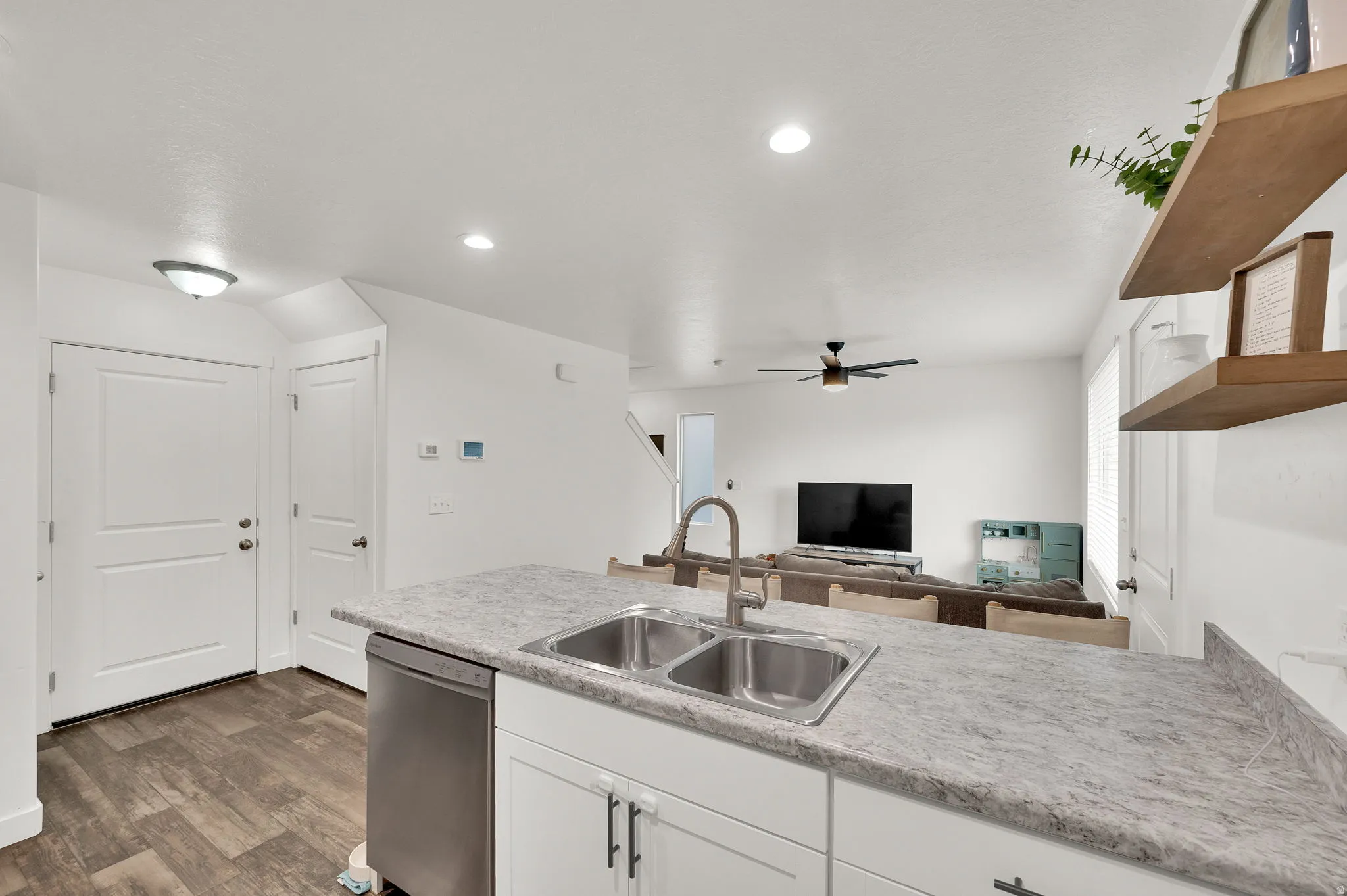 Kitchen featuring open floor plan, light countertops, dishwasher, white cabinets, and a ceiling fan