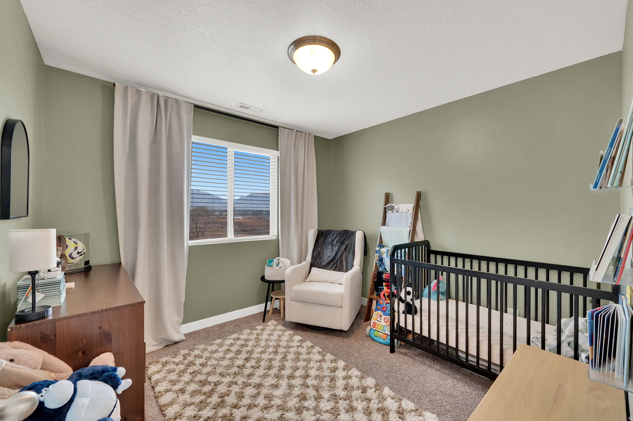 Carpeted bedroom with a crib and a textured ceiling