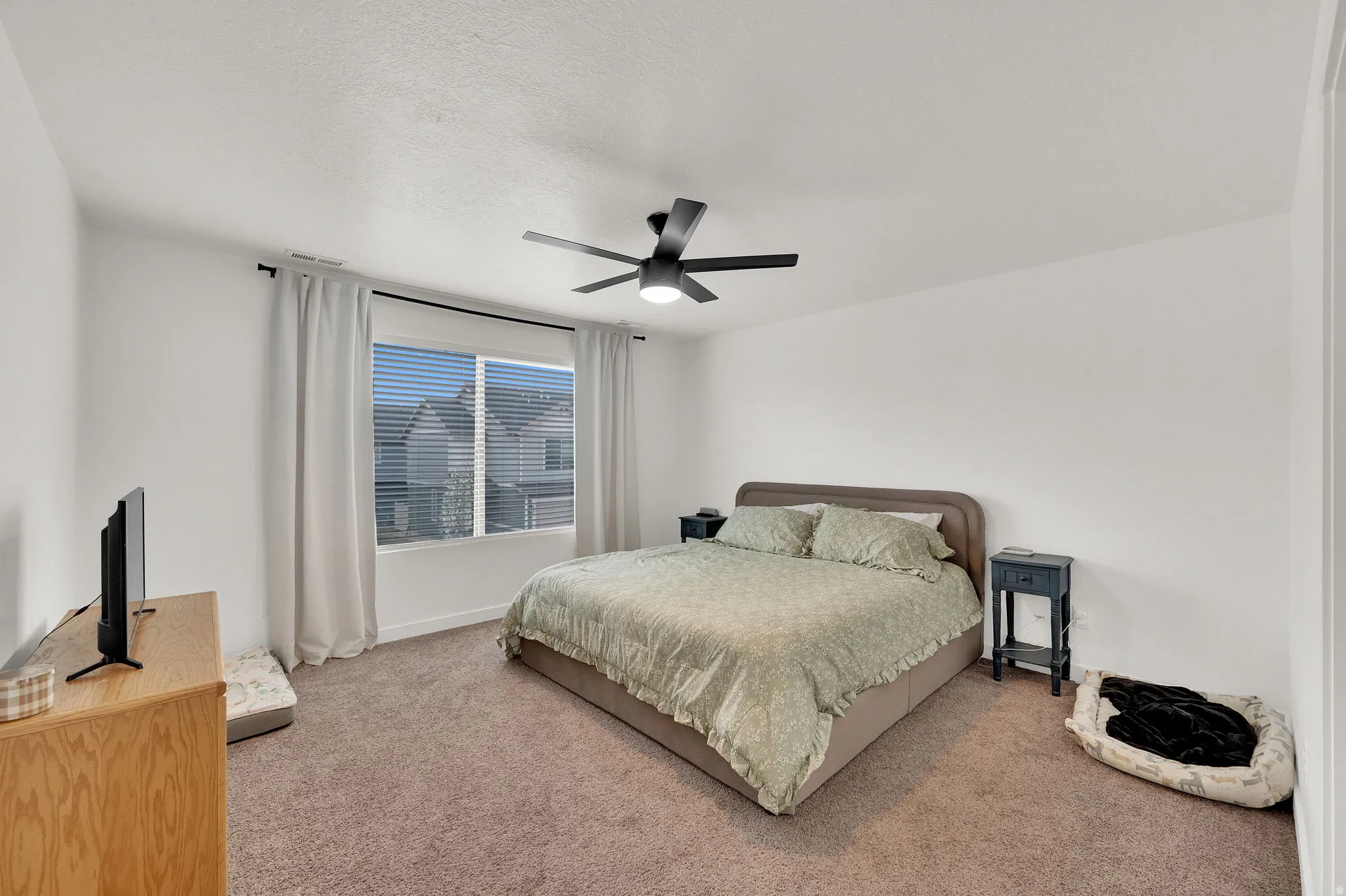 Bedroom featuring ceiling fan, carpet floors, and a textured ceiling
