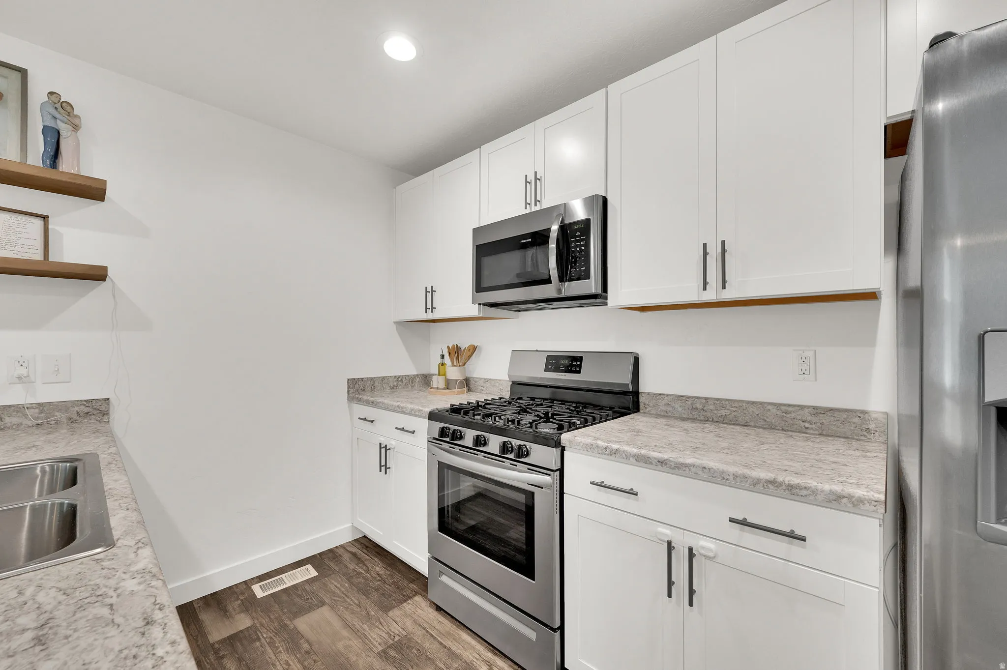 Kitchen with stainless steel appliances, open shelves, white cabinetry, dark wood-style floors, and recessed lighting