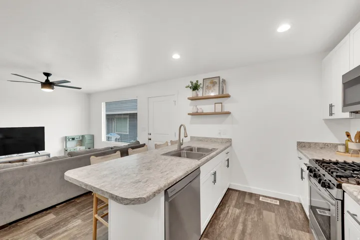 Kitchen with a peninsula, a kitchen breakfast bar, white cabinetry, open floor plan, and recessed lighting