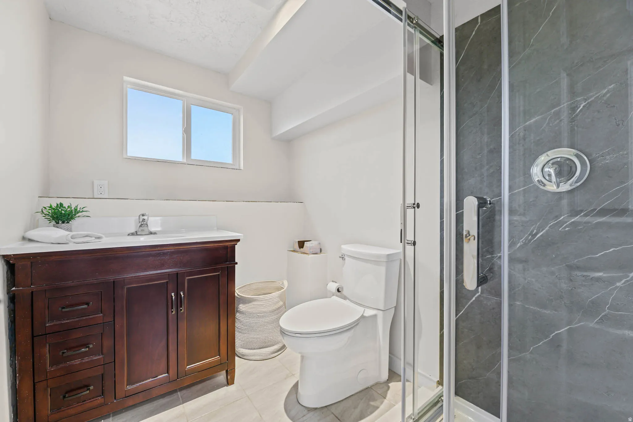 Bathroom featuring vanity, a marble finish shower, and light tile patterned floors