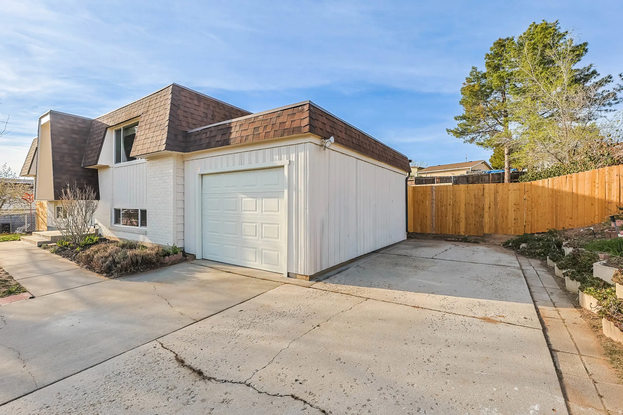 View of home's exterior featuring mansard roof, brick & siding, a single car garage, and concrete driveway