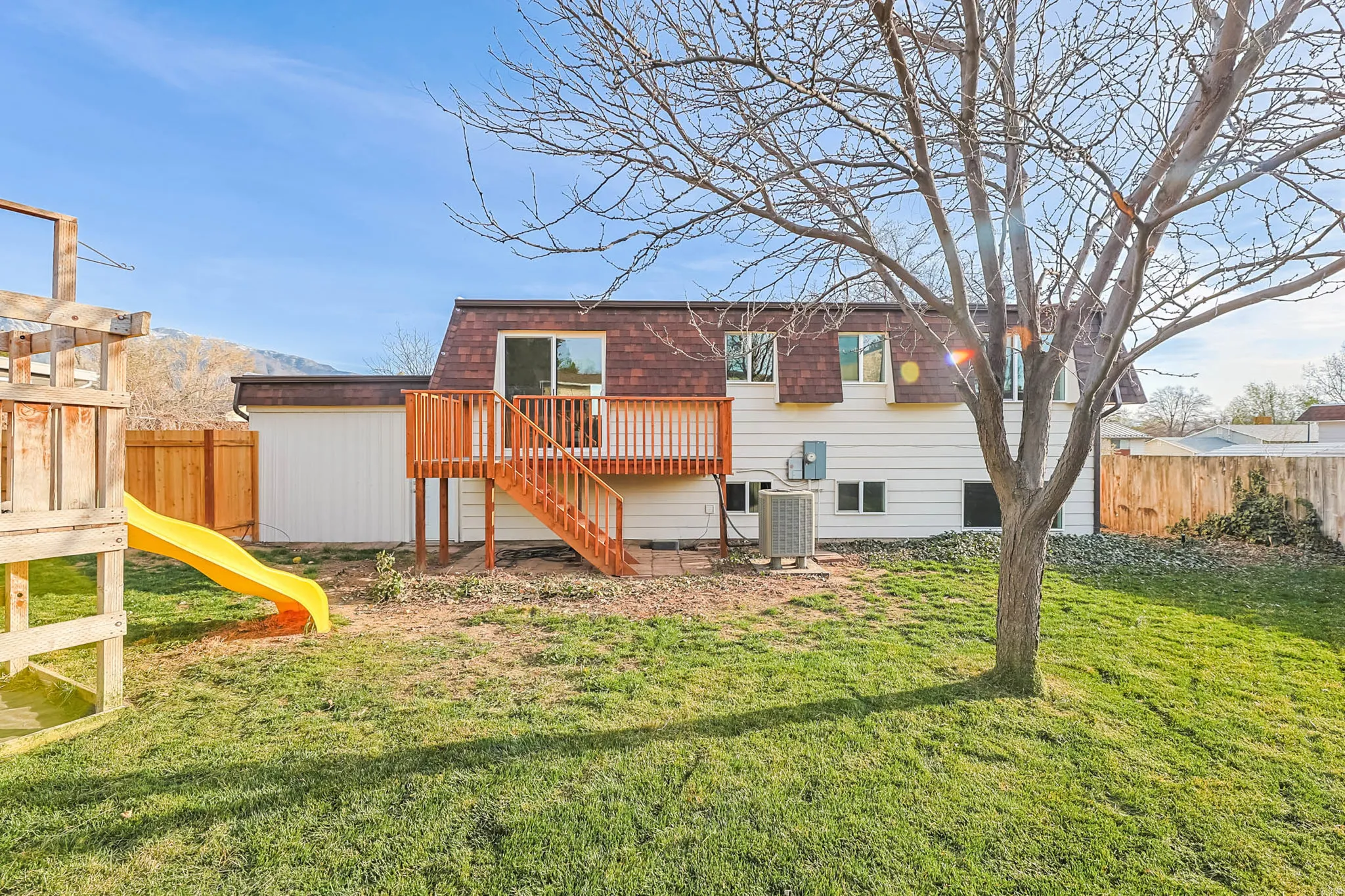 Rear view of property featuring a playground, and mansard roof