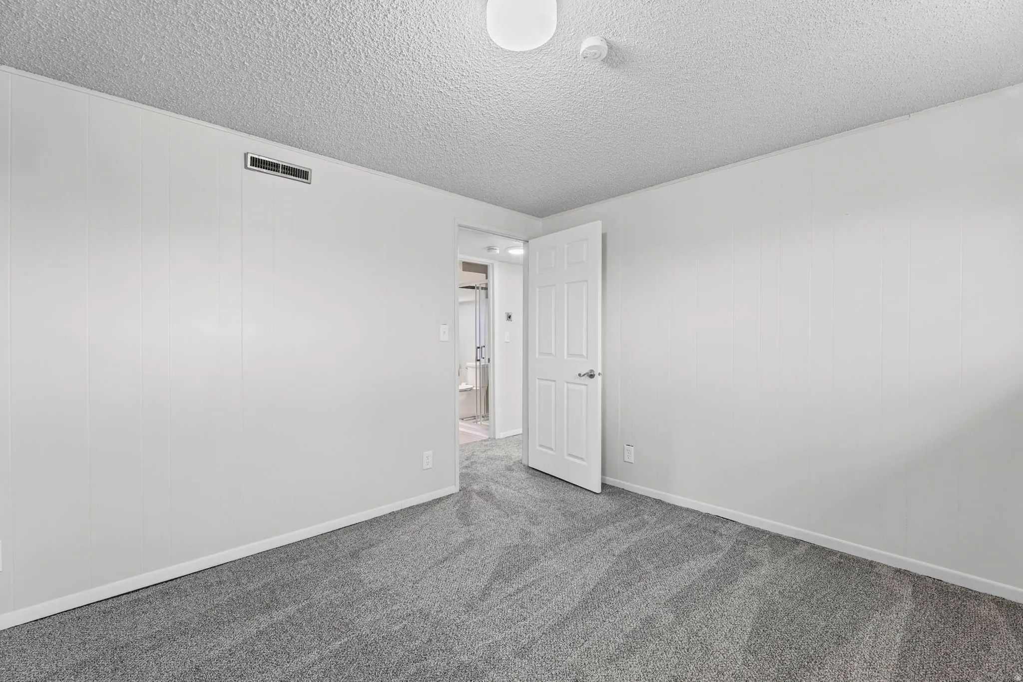 Unfurnished room with dark carpet and a textured ceiling