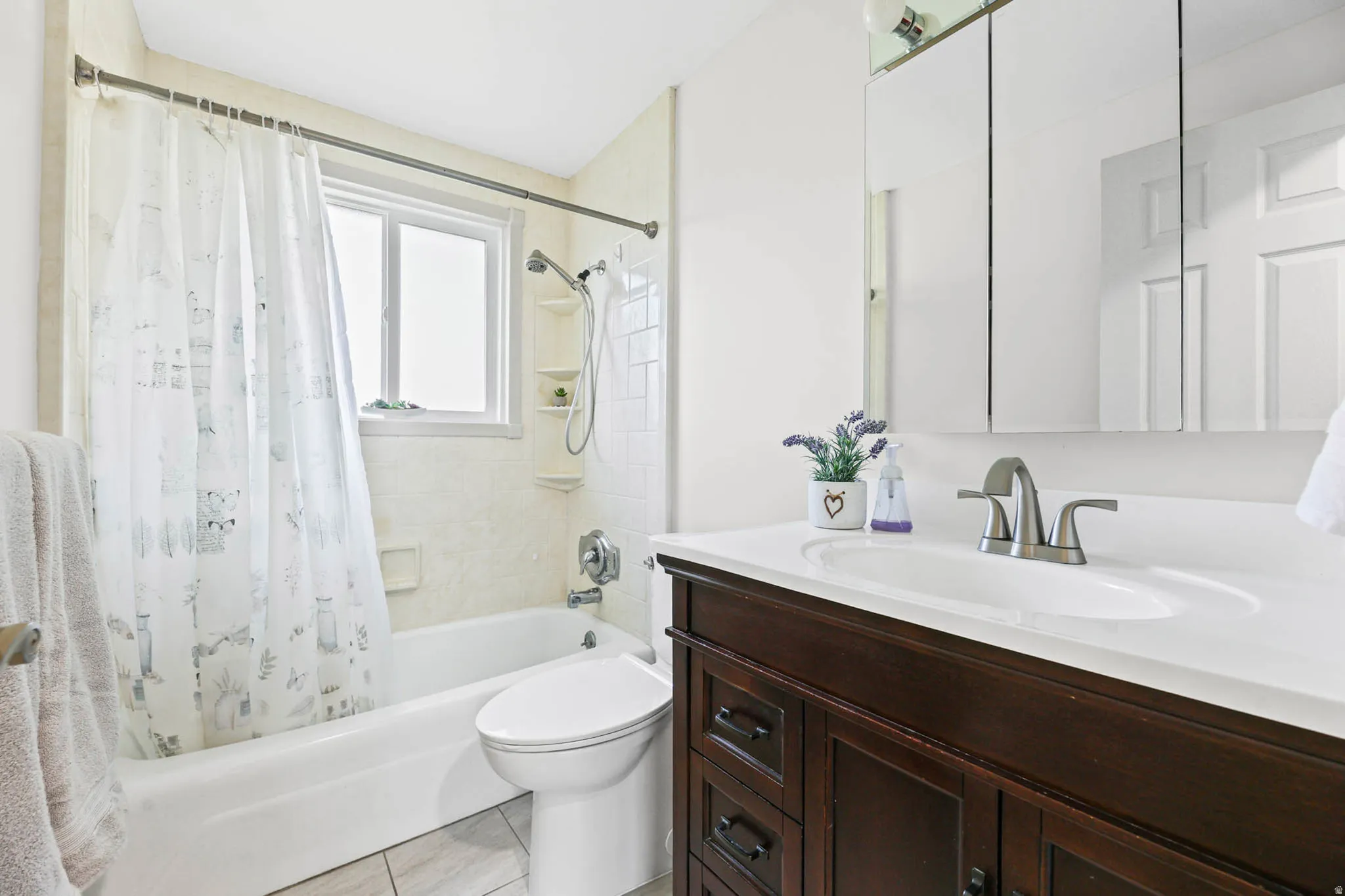Full bath featuring vanity, shower / tub combo, and light tile patterned flooring