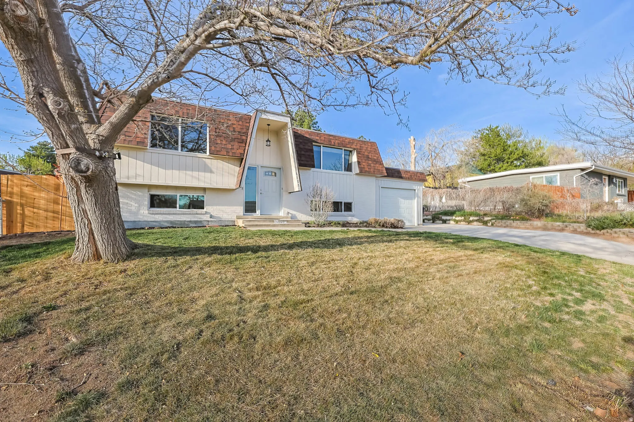 A-frame home featuring mansard roof, driveway, a garage and new windows.