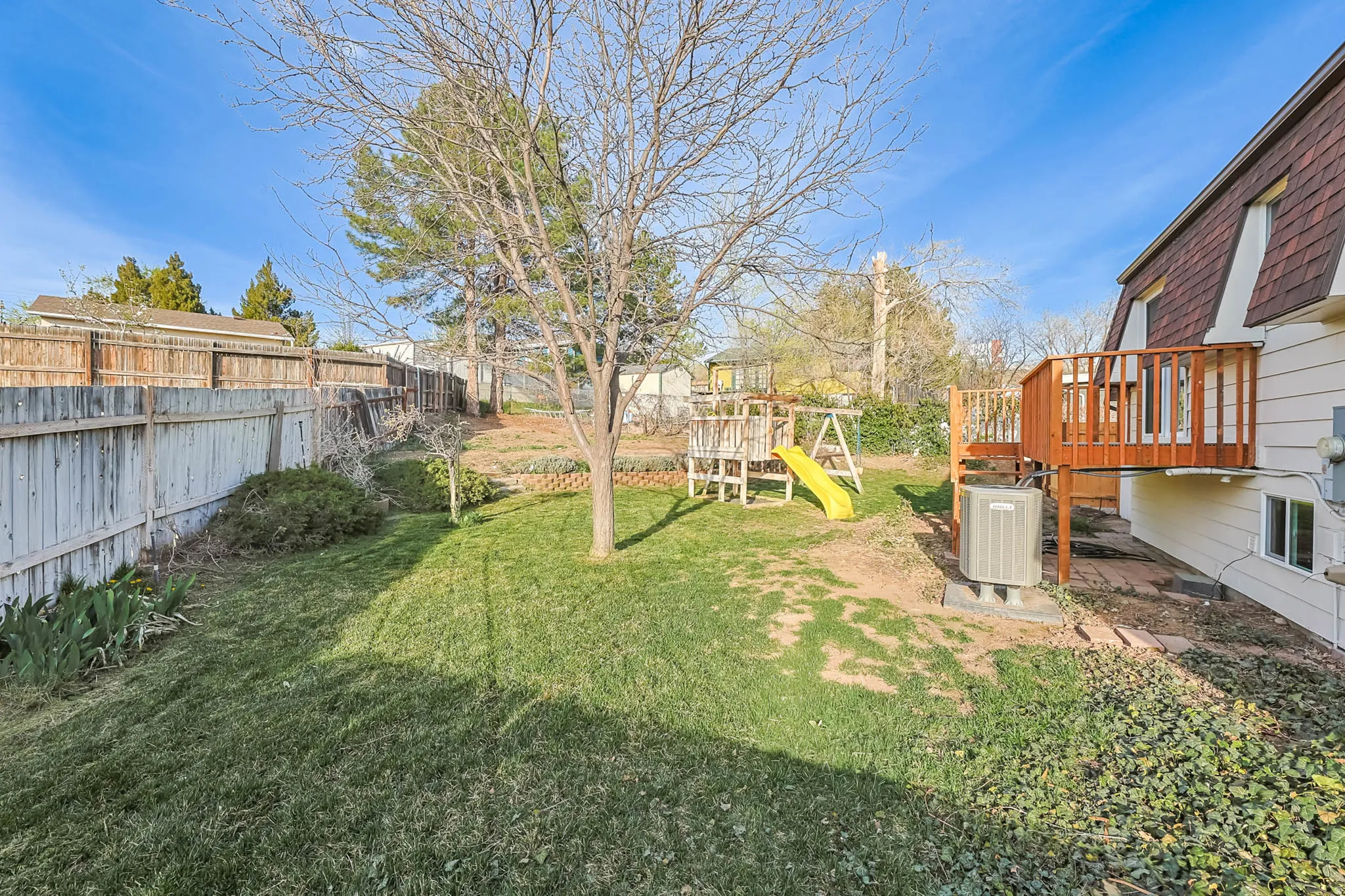 Fenced backyard featuring a playground and a deck