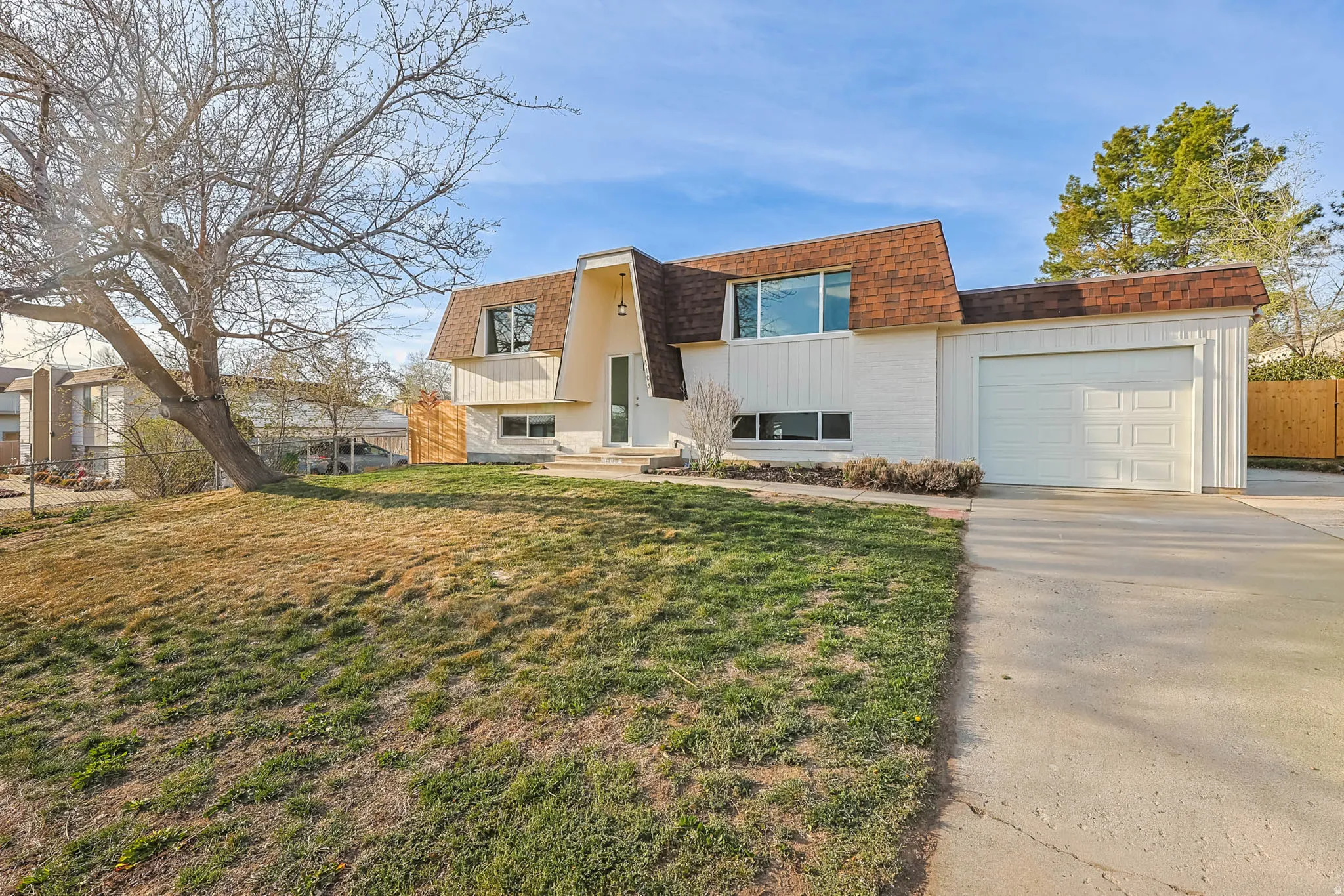 View of front of home with mansard roof, a garage, and driveway