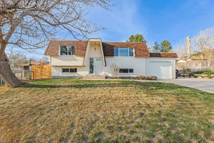 View of front of property with mansard roof, concrete driveway, an attached garage, and a shingled roof