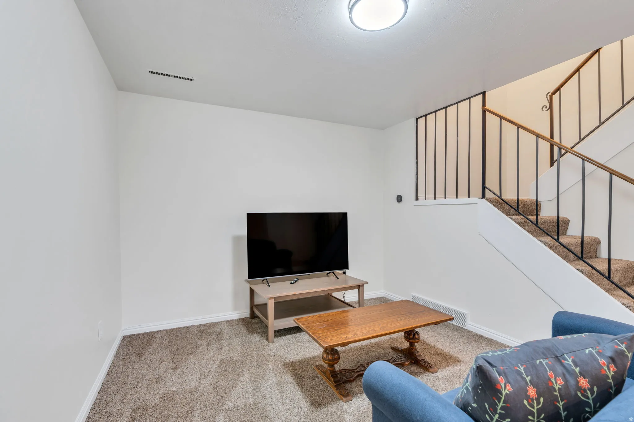 Living area with light colored carpet and stairway