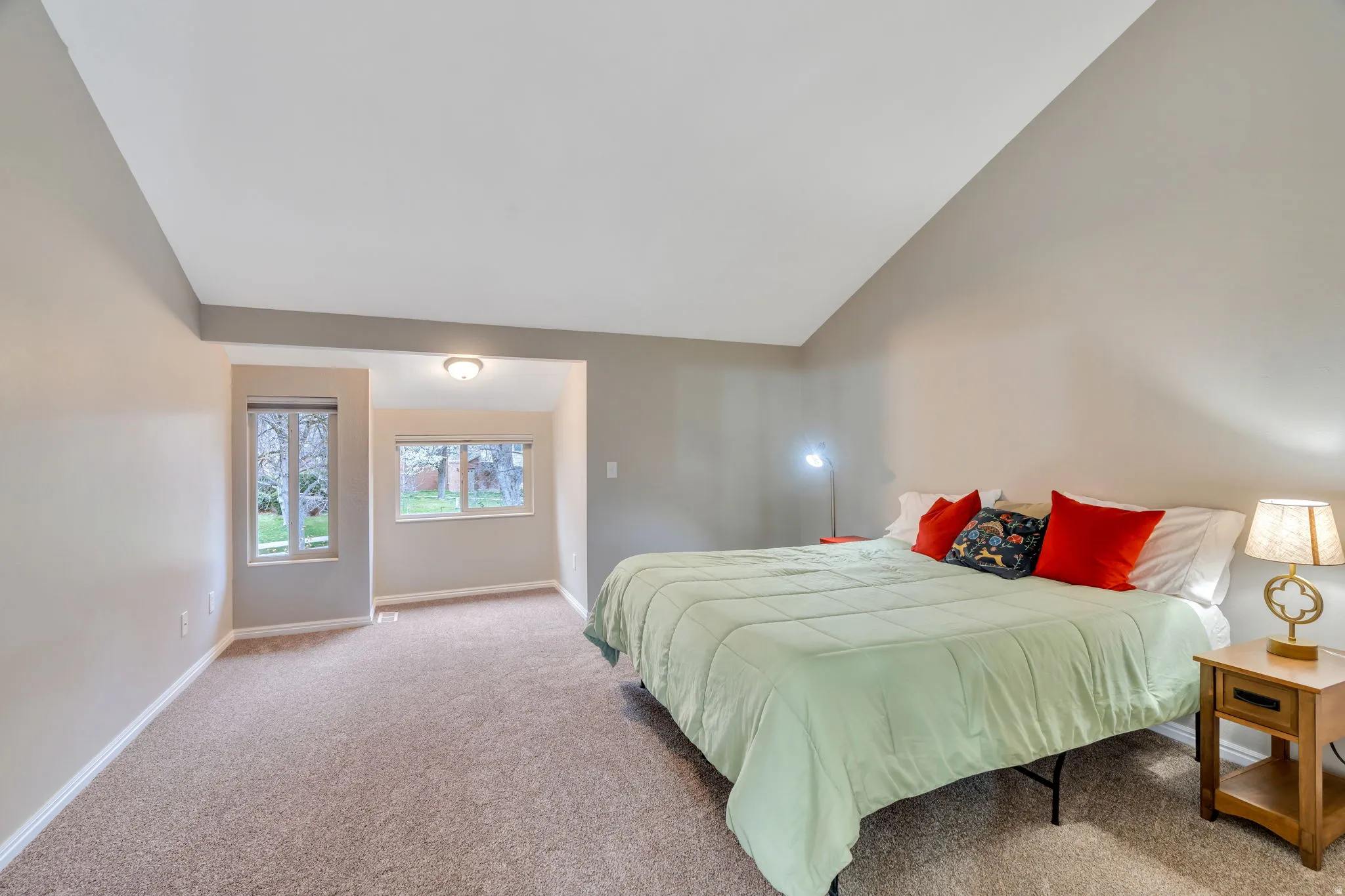 Bedroom with light carpet and vaulted ceiling