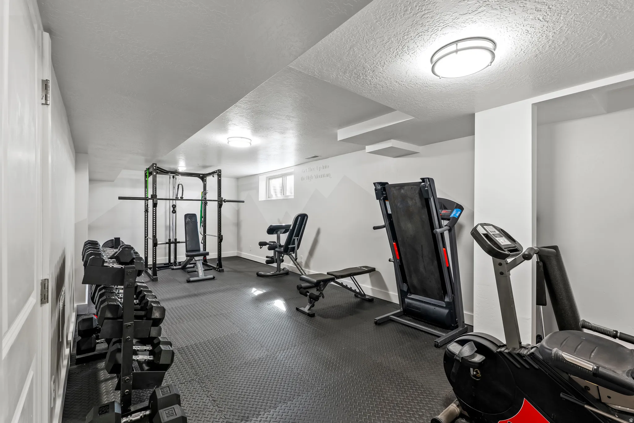 Exercise room with a textured ceiling and dark rubber floors