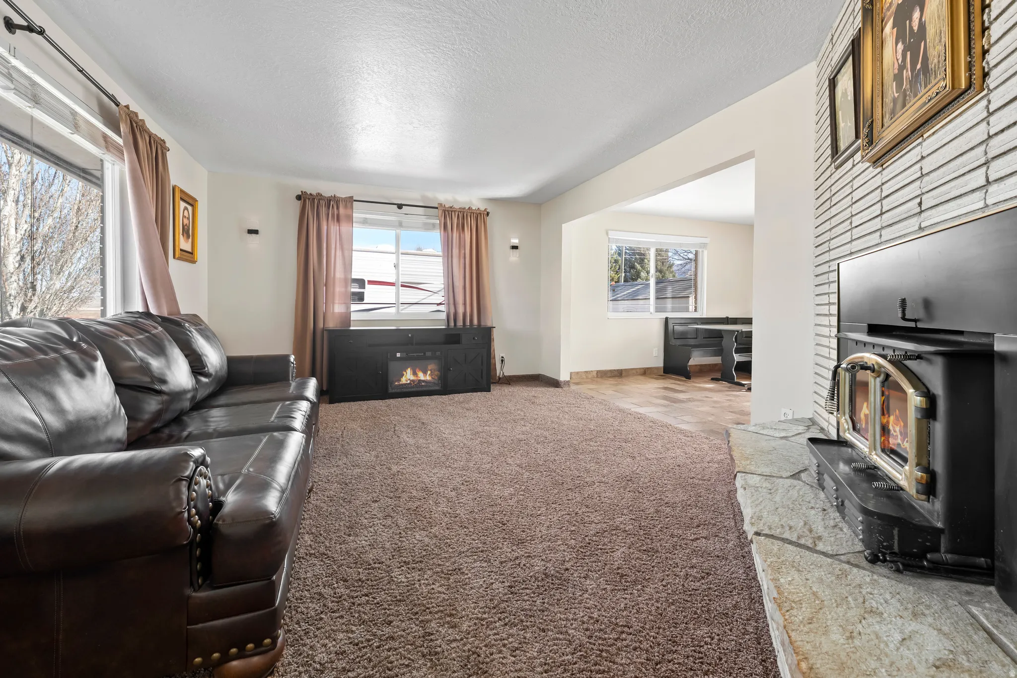 Living room featuring light carpet, a fireplace, and a textured ceiling