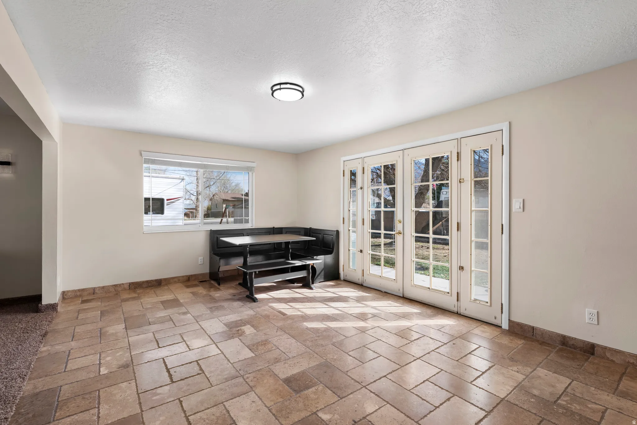 Sitting room featuring french doors, stone tile flooring, and a textured ceiling