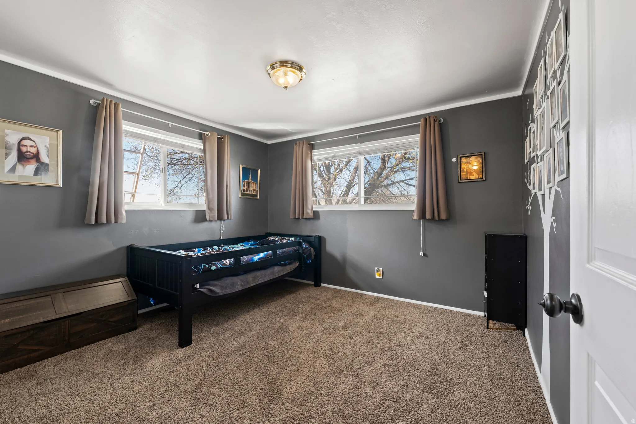 Bedroom with dark colored carpet and multiple windows
