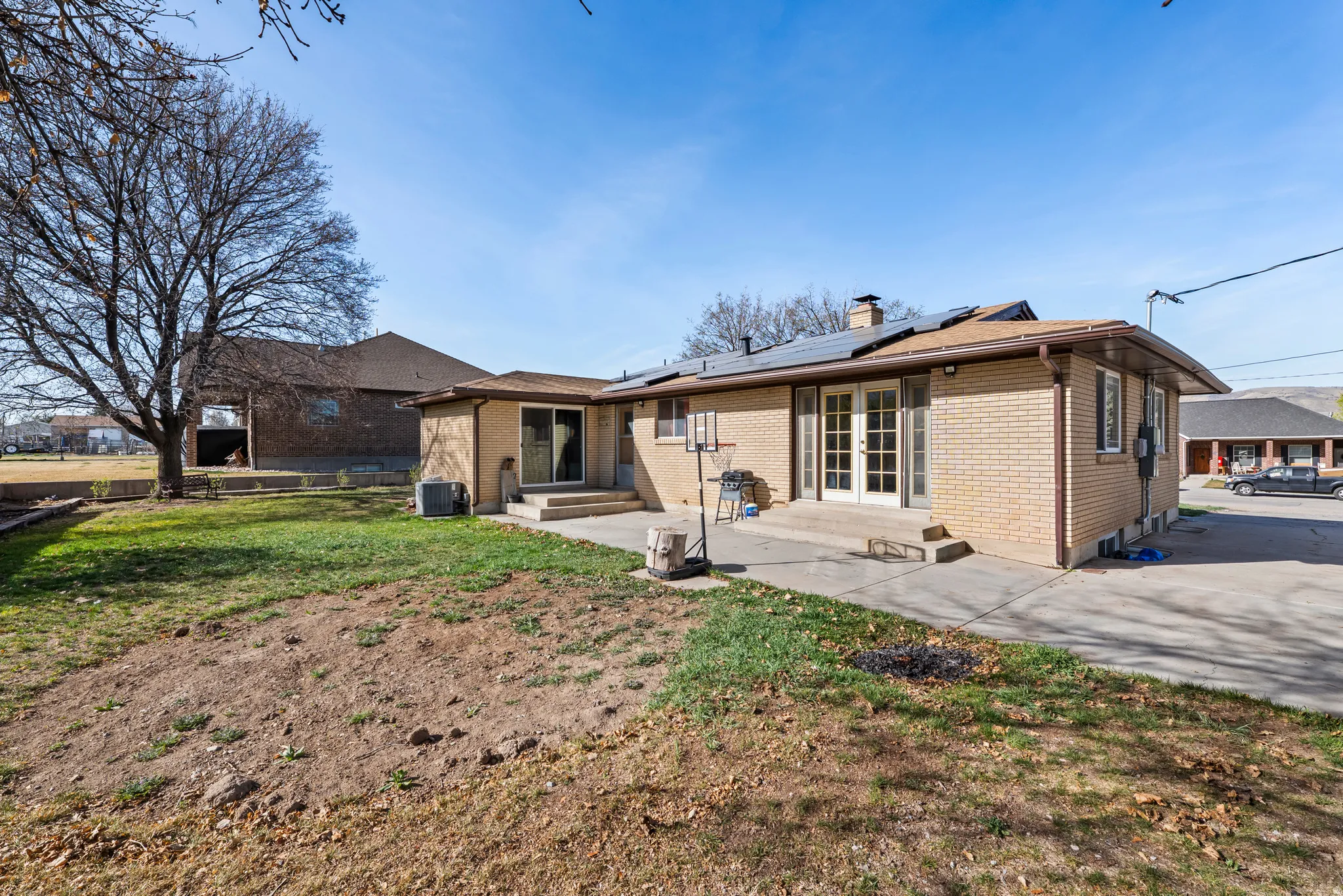Back of property with solar panels, brick siding, french doors, and a lawn
