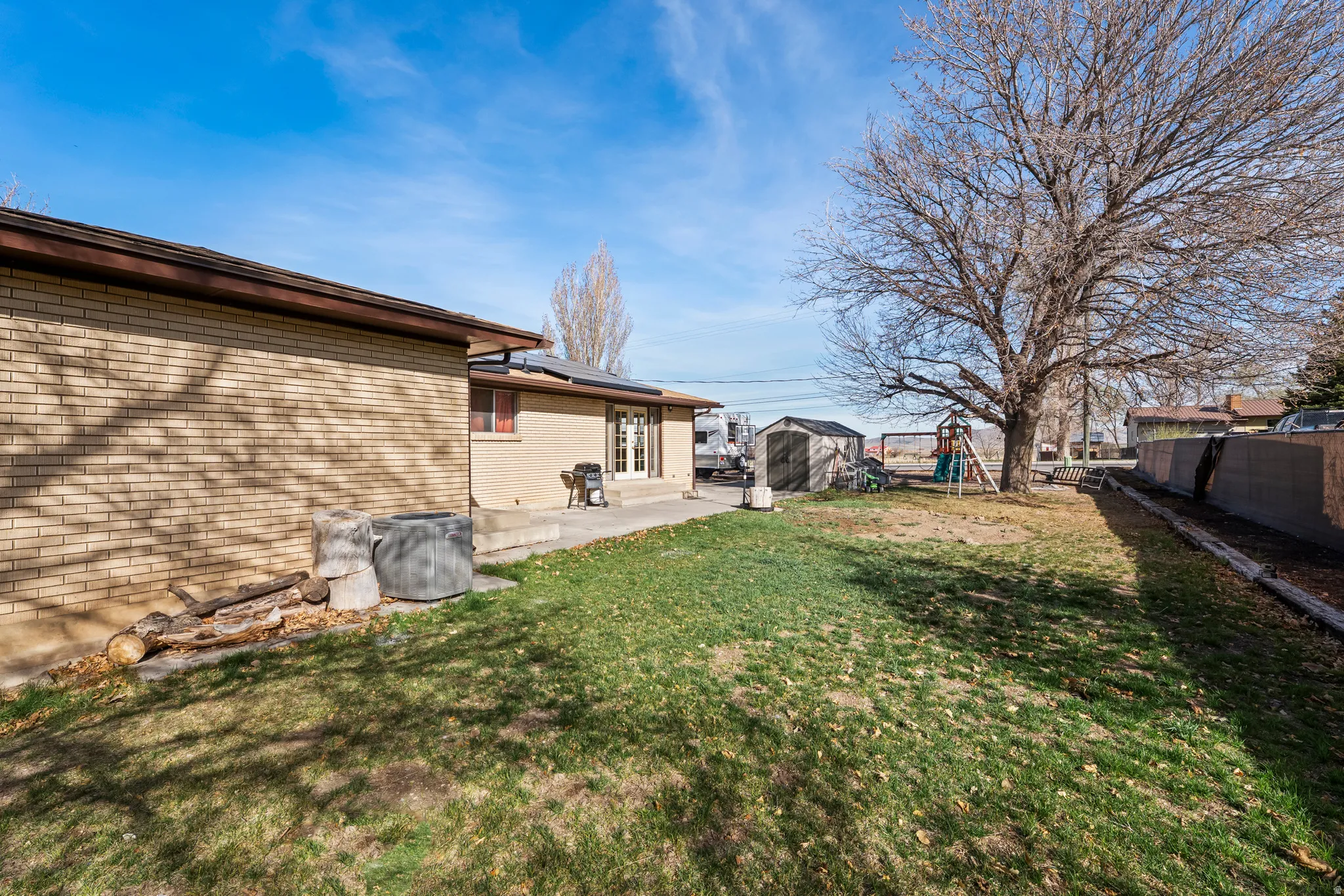 Fenced backyard with a shed, a patio, and a playground