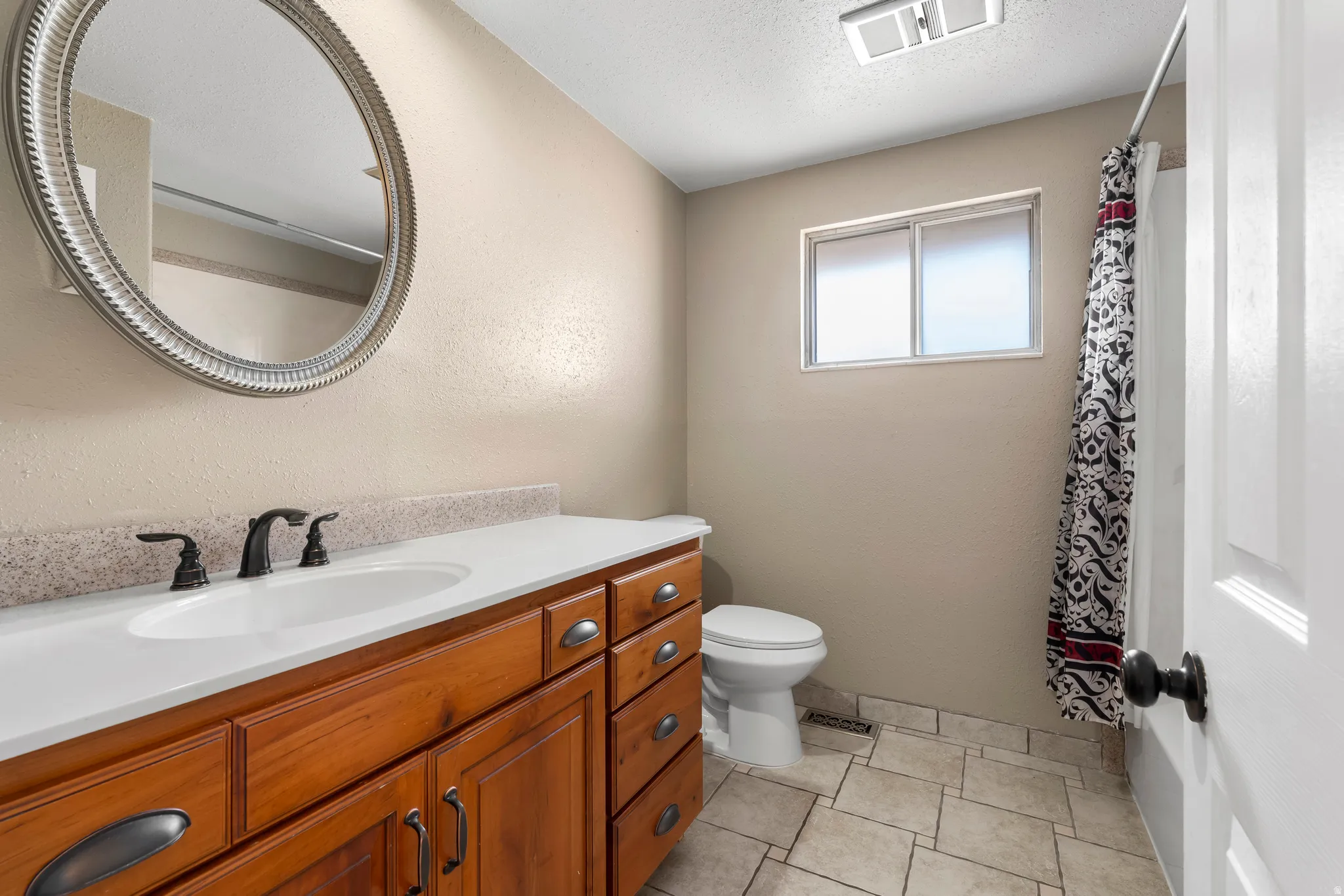 Full bath featuring curtained shower, vanity, a textured ceiling, and a textured wall
