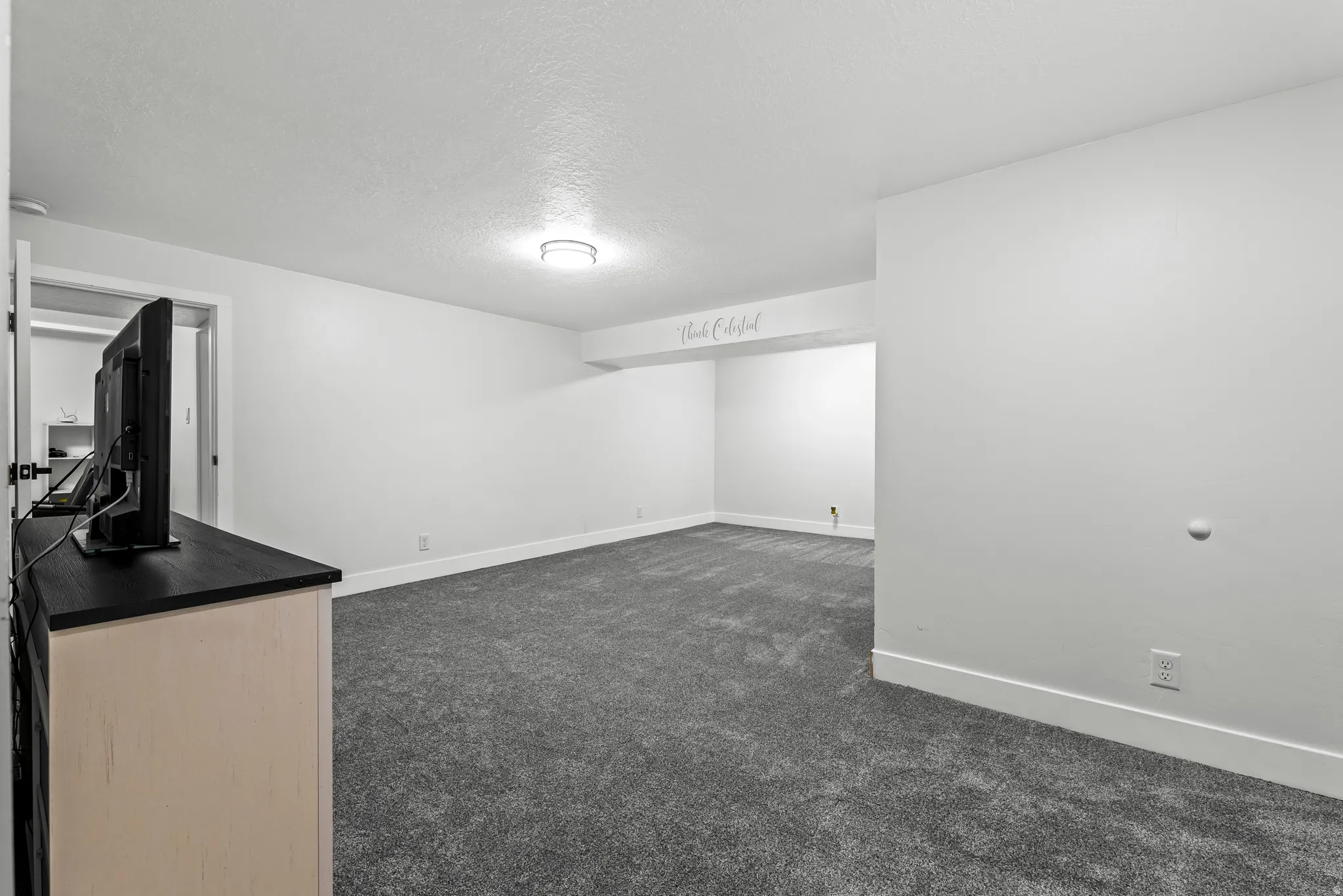 Finished below grade area featuring dark colored carpet and a textured ceiling