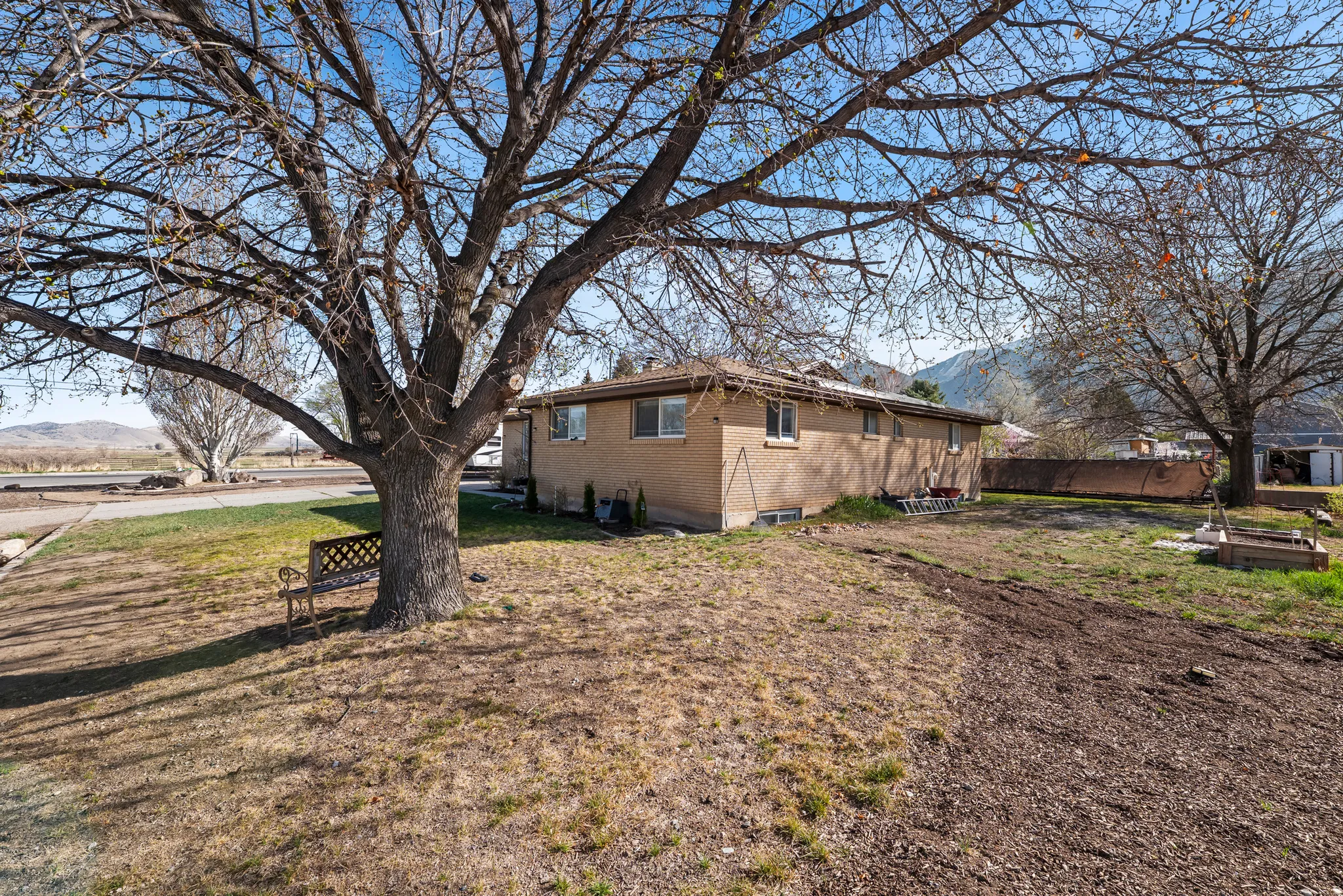 View of side of property with brick siding, a mountain view, and a yard