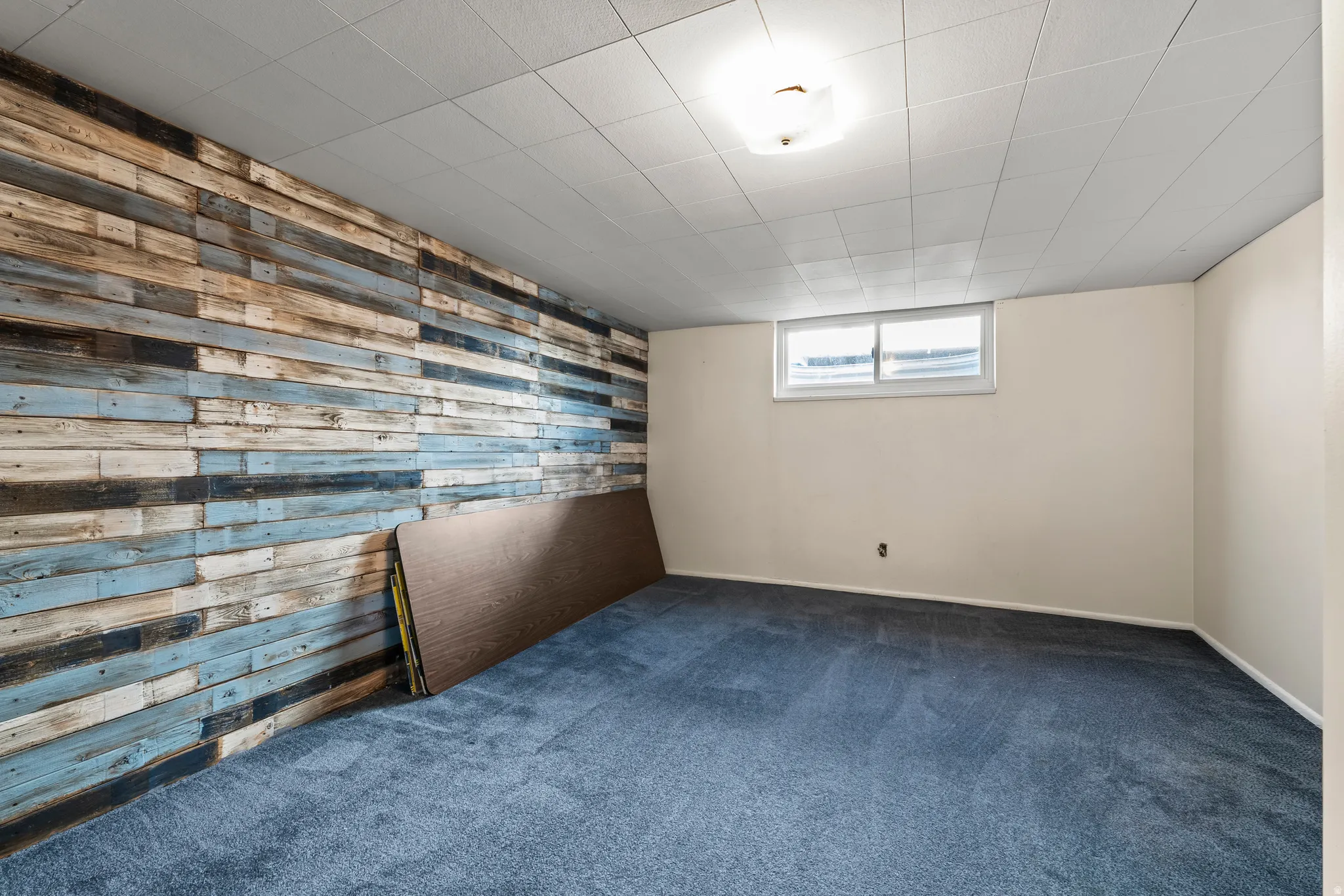 Spare room featuring wooden walls, dark carpet, and an accent wall