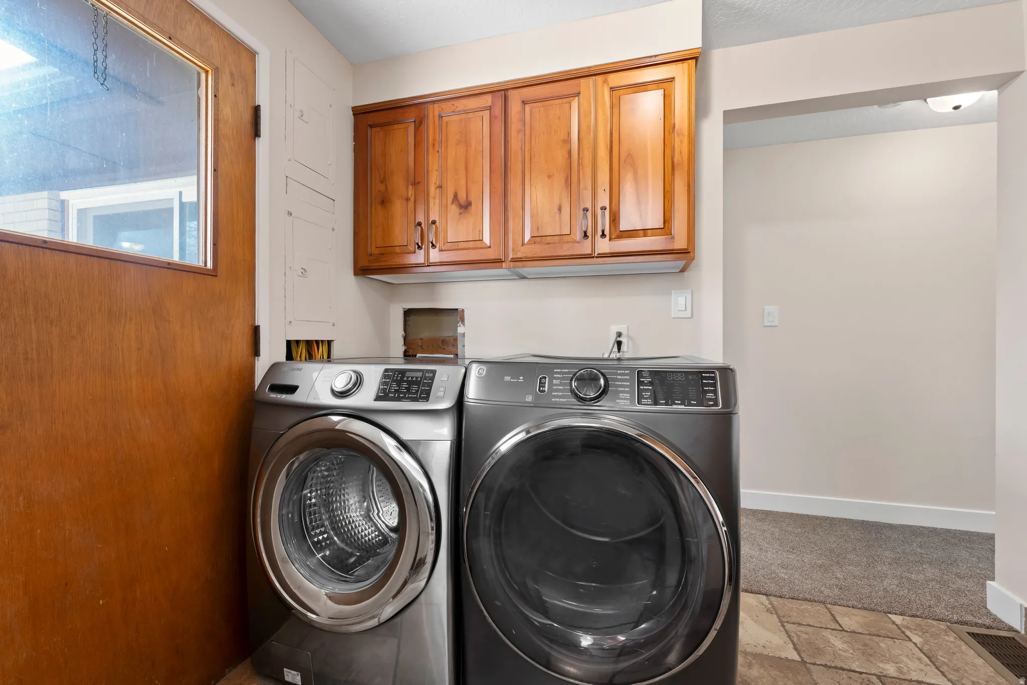 Laundry area with stone tile flooring, washing machine and dryer, and cabinet space