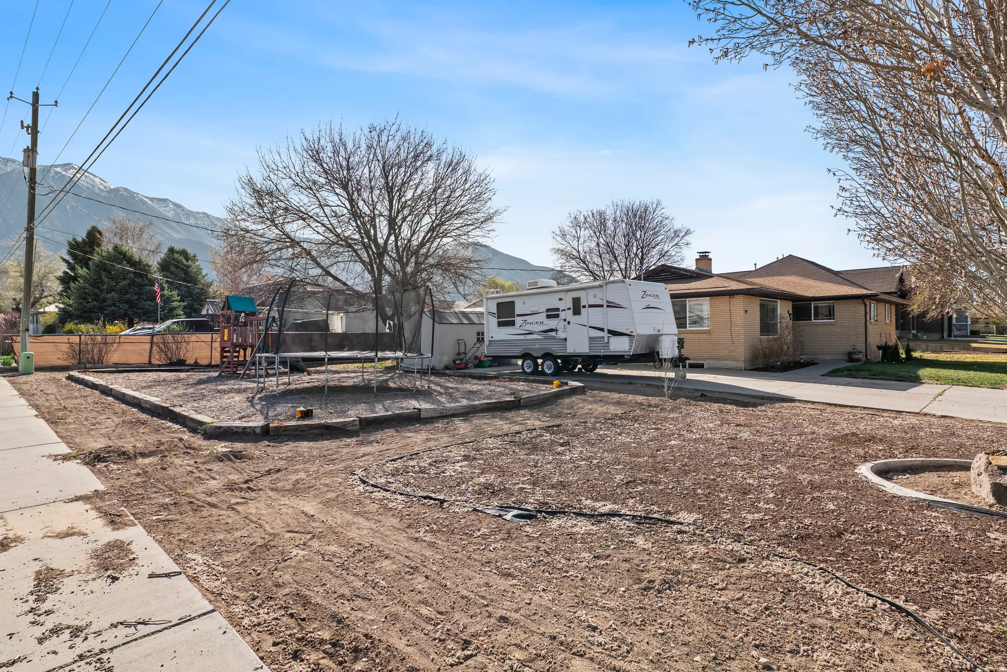 View of front of home with a trampoline, a chimney, a mountain view, brick siding, and a playground
