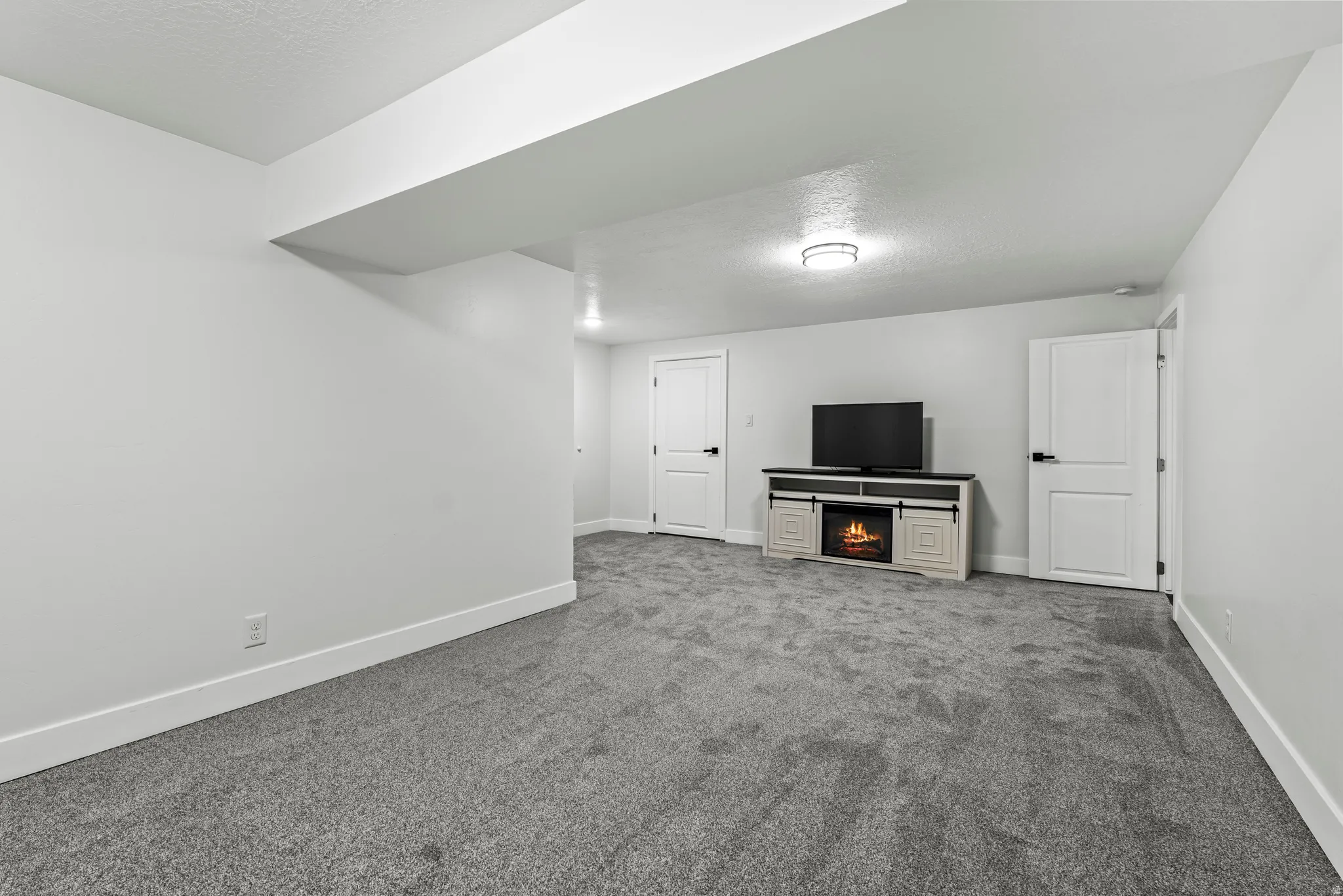 Unfurnished living room featuring carpet floors, a textured ceiling, and a warm lit fireplace