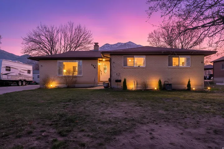 View of front of house featuring a chimney, brick siding, and a lawn