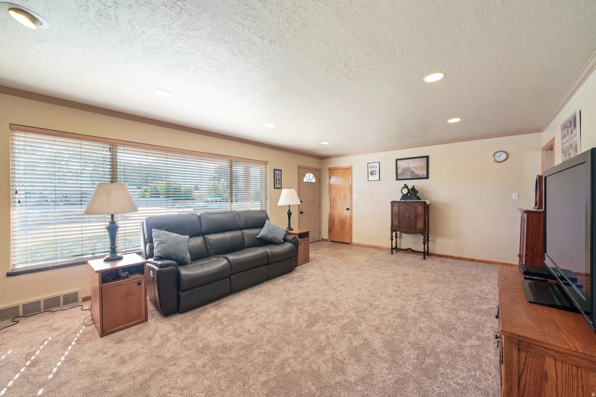 Living room with crown molding, light colored carpet, a textured ceiling, and recessed lighting
