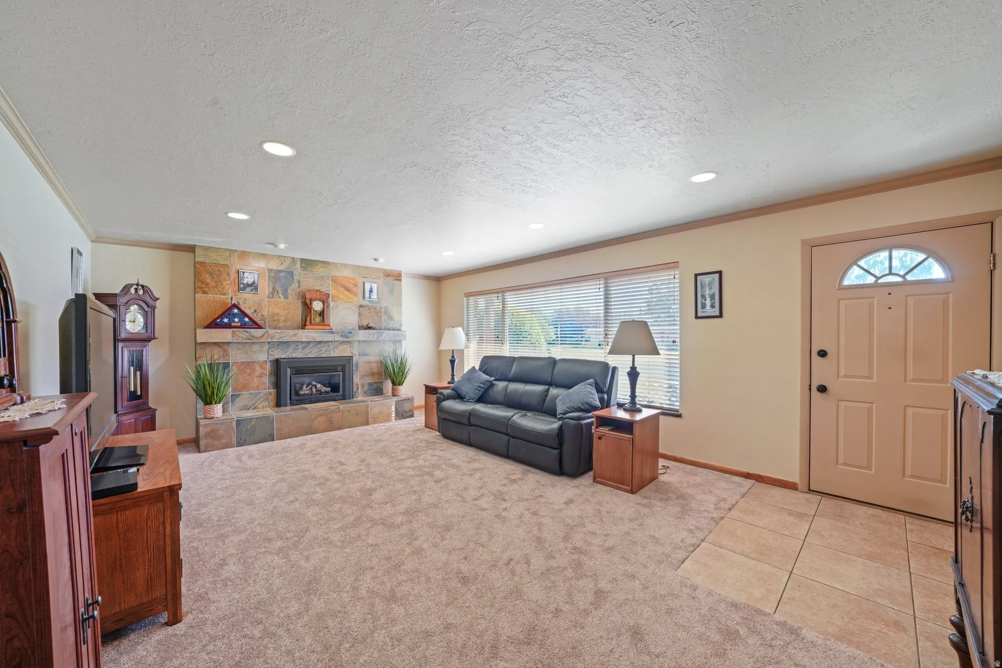 Living room featuring light colored carpet, a tiled fireplace, light tile patterned floors, a textured ceiling, and recessed lighting