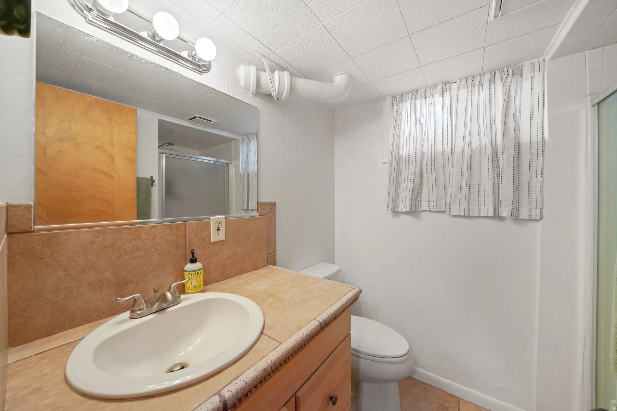 Bathroom with vanity, a stall shower, and backsplash