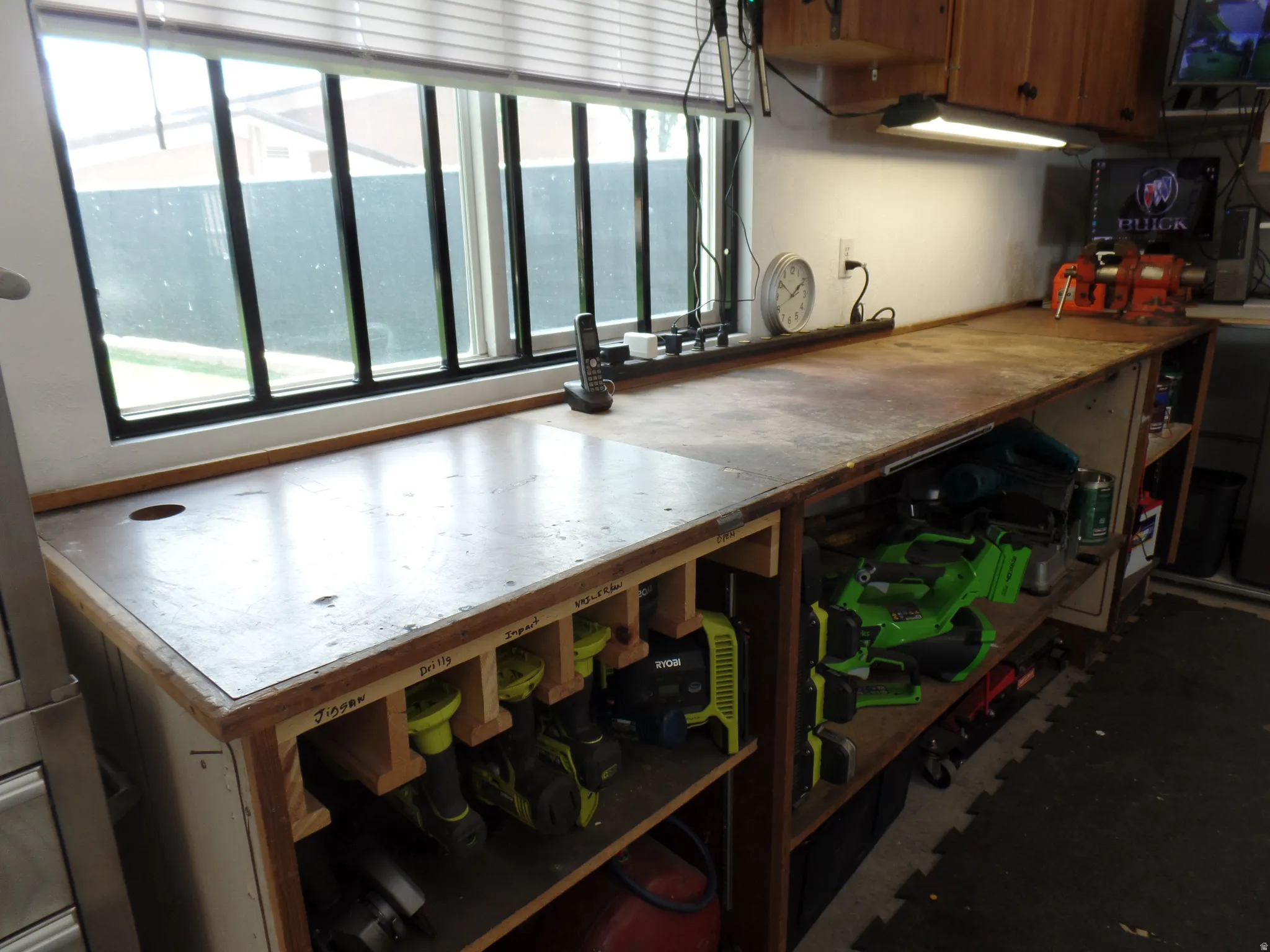 Custom built-in workbench featuring wood-finish cabinetry, integrated shelving, and a large window providing natural illumination