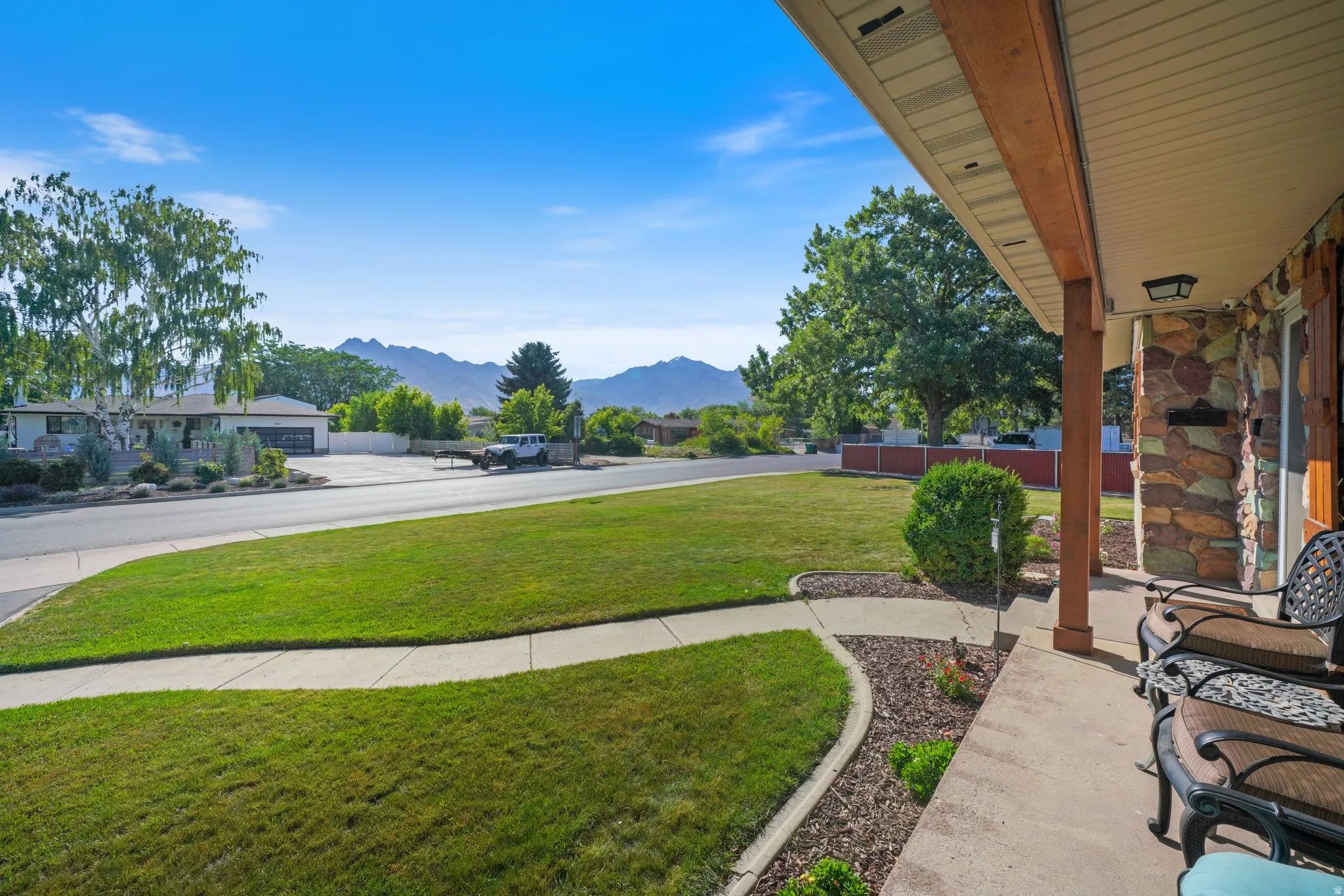 View of grassy yard with a mountain view and covered porch
