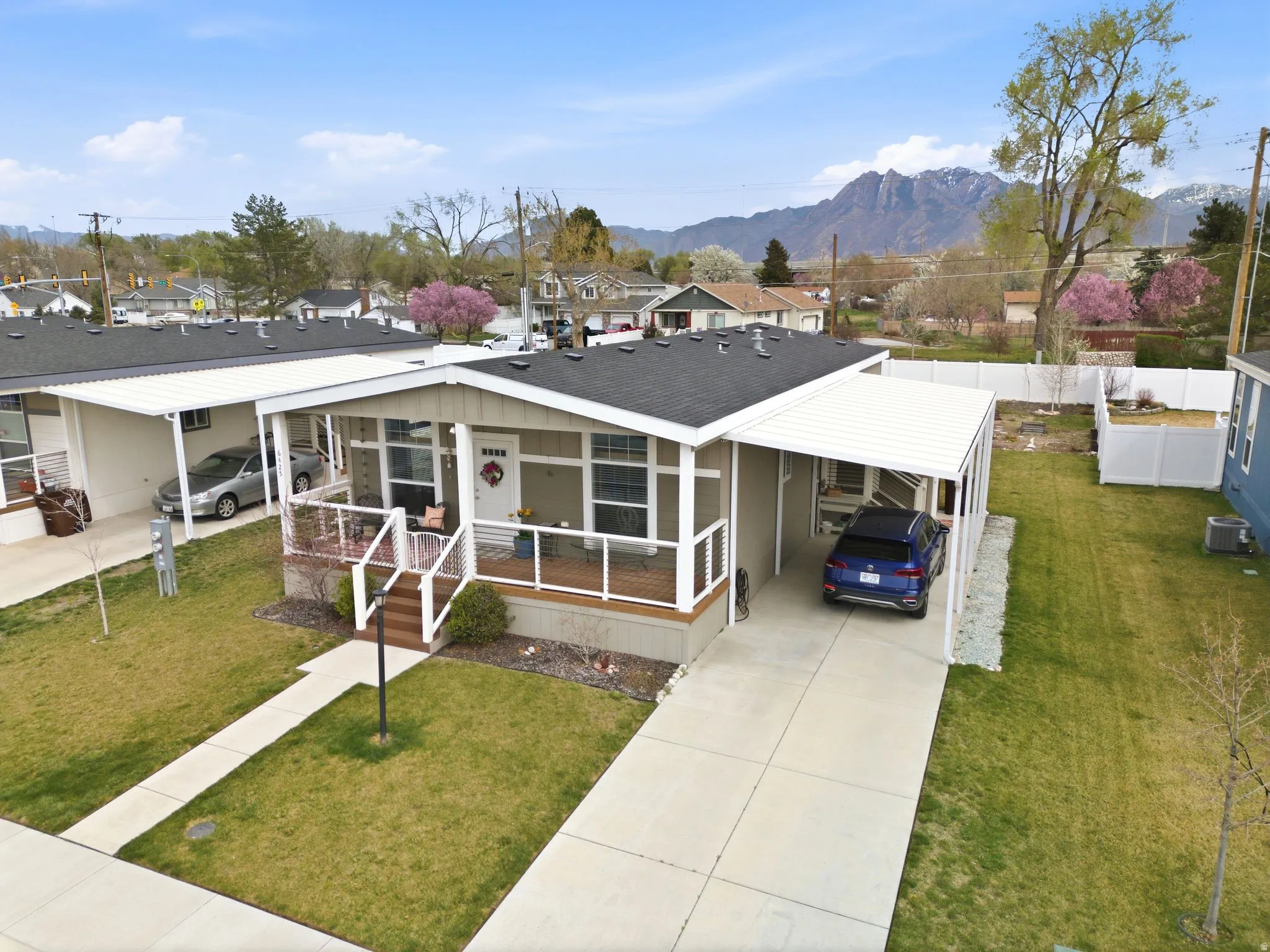 View of front facade with a front yard, a carport, concrete driveway, a shingled roof, and a residential view