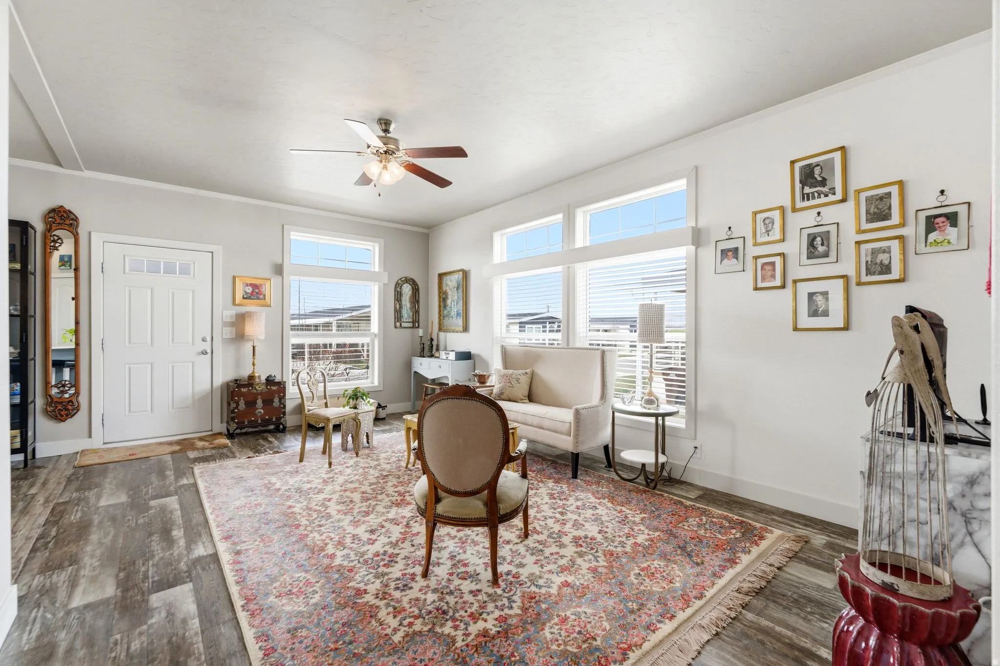 Living area with crown molding, dark wood finished floors, and ceiling fan