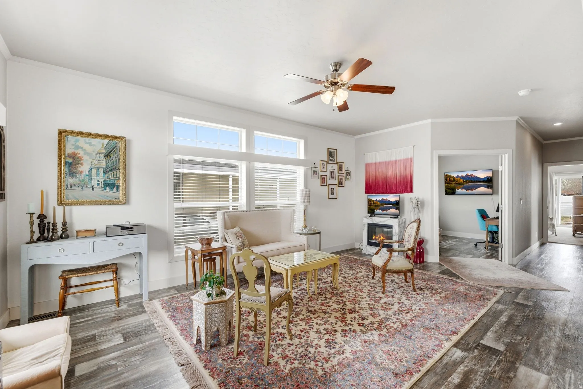 Living room with ornamental molding, a ceiling fan, dark wood finished floors, and a glass covered fireplace