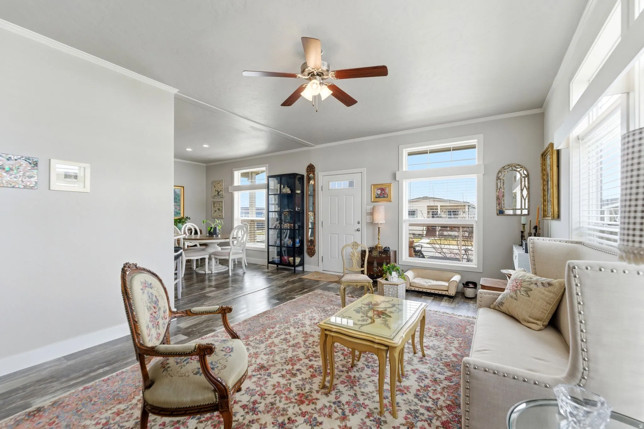 Living room with ornamental molding, a ceiling fan, and wood finished floors
