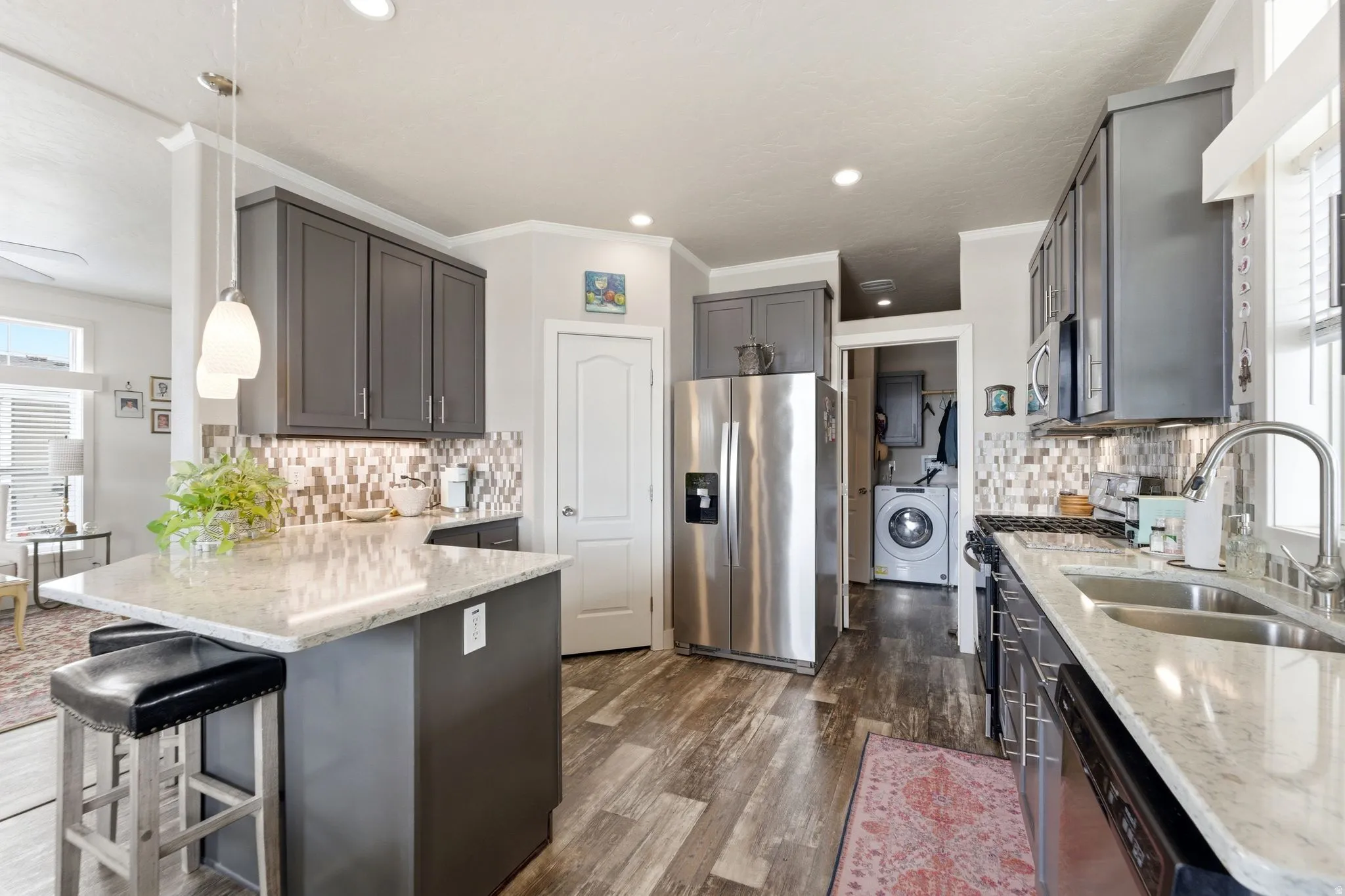 Kitchen featuring plenty of natural light, stainless steel appliances, light stone countertops, a peninsula, and crown molding