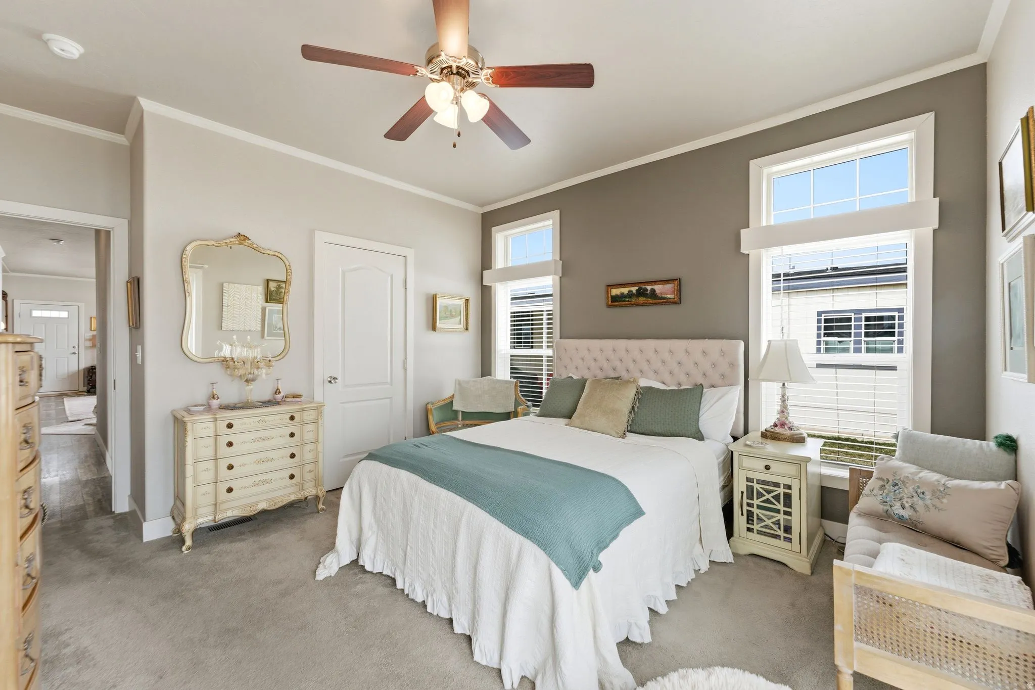 Carpeted bedroom with ornamental molding, multiple windows, and ceiling fan