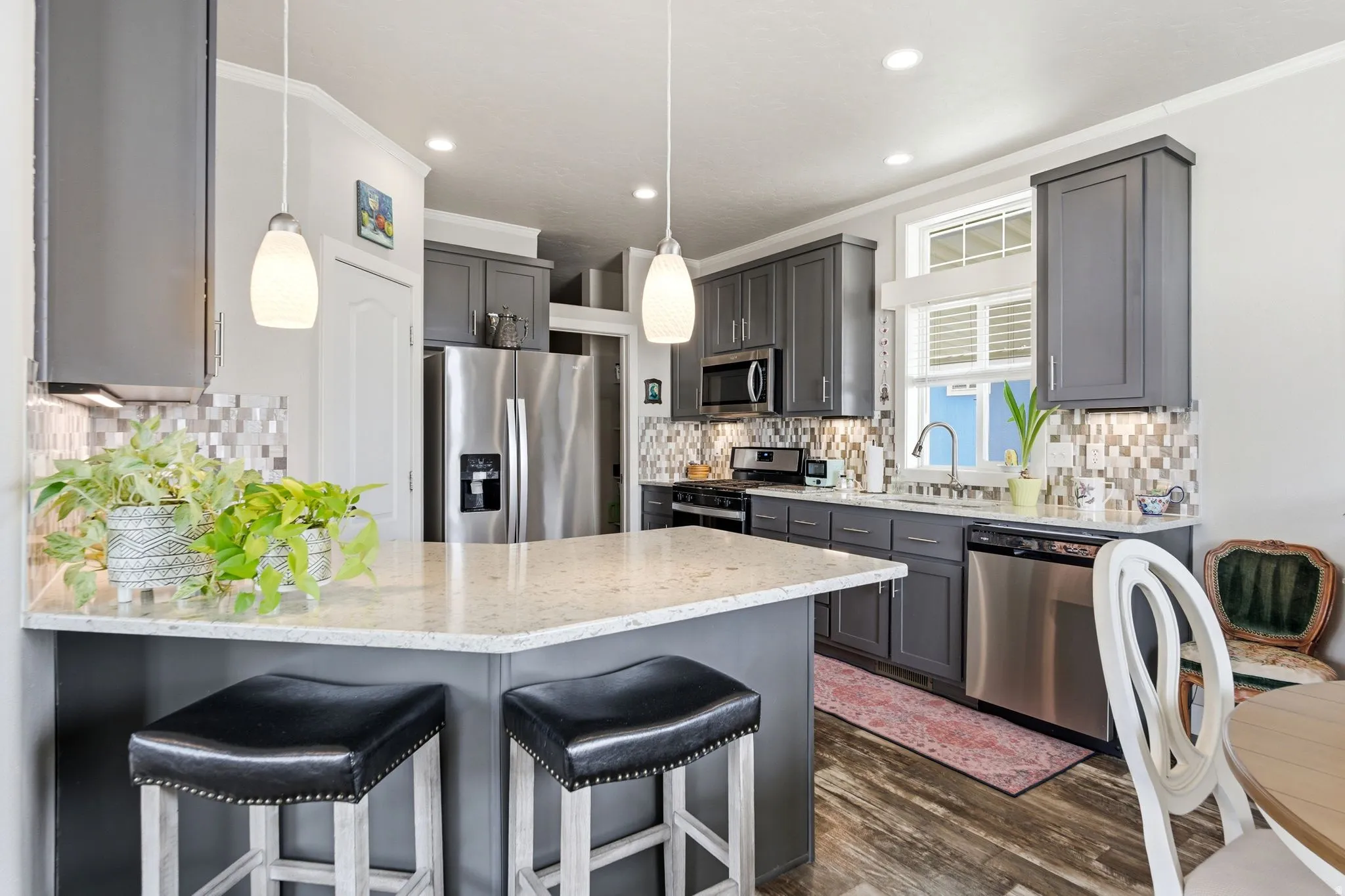 Kitchen with light stone countertops, a kitchen breakfast bar, stainless steel appliances, a peninsula, and ornamental molding