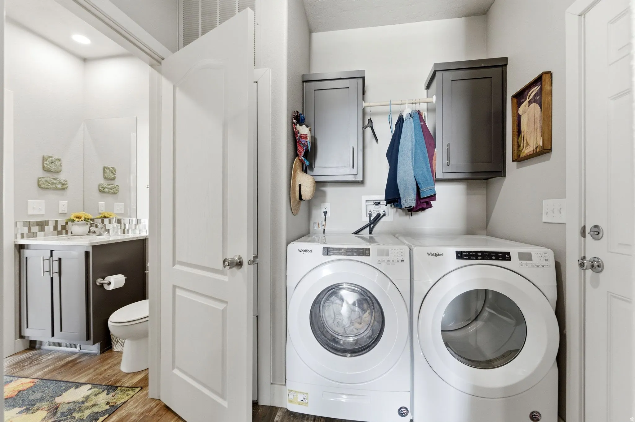 Laundry room with light wood-style floors, washing machine and clothes dryer, and cabinet space